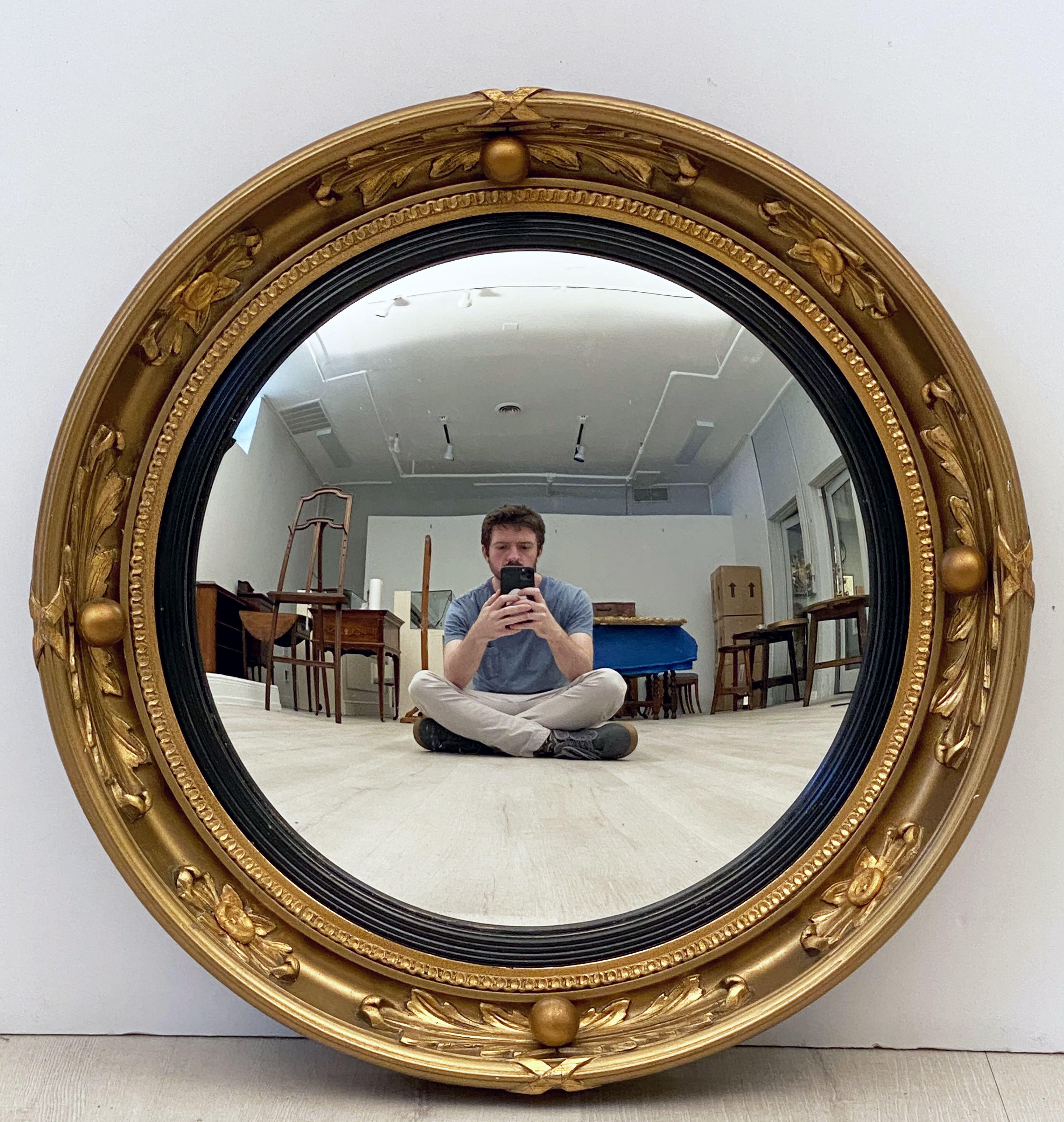 A fine English round or circular convex mirror featuring a Regency design of a moulded gilt frame and ebonized trim, with gilt balls and acanthus leaves around the circumference.

Dimensions: Diameter 16 1/2 inches x Depth 2 inches.