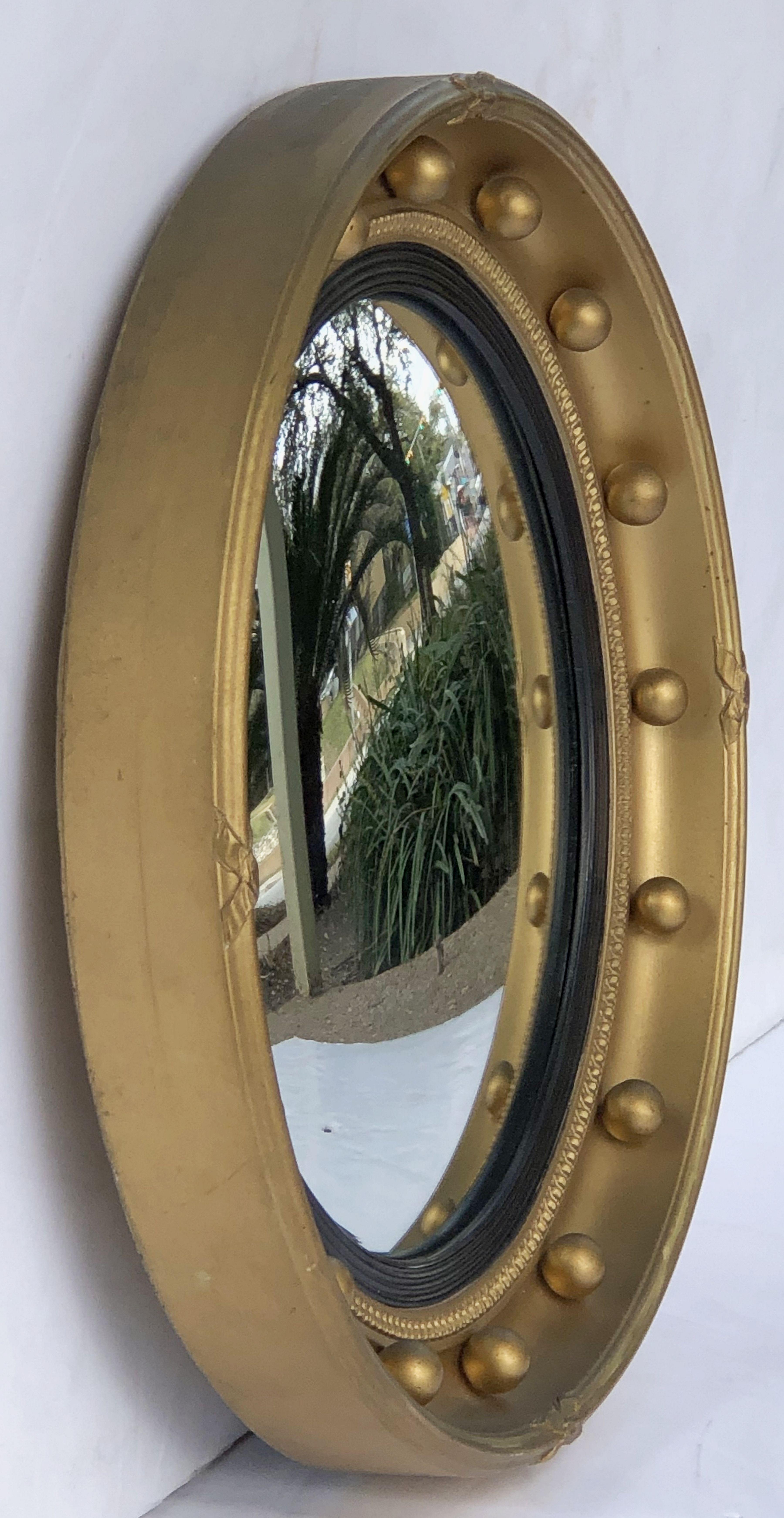 A fine English round or circular convex mirror featuring a Regency design of a moulded gilt frame and ebonized trim, with gilt balls around the circumference.

Dimensions: Diameter 16 1/4 inches x Depth 2 1/4 inches