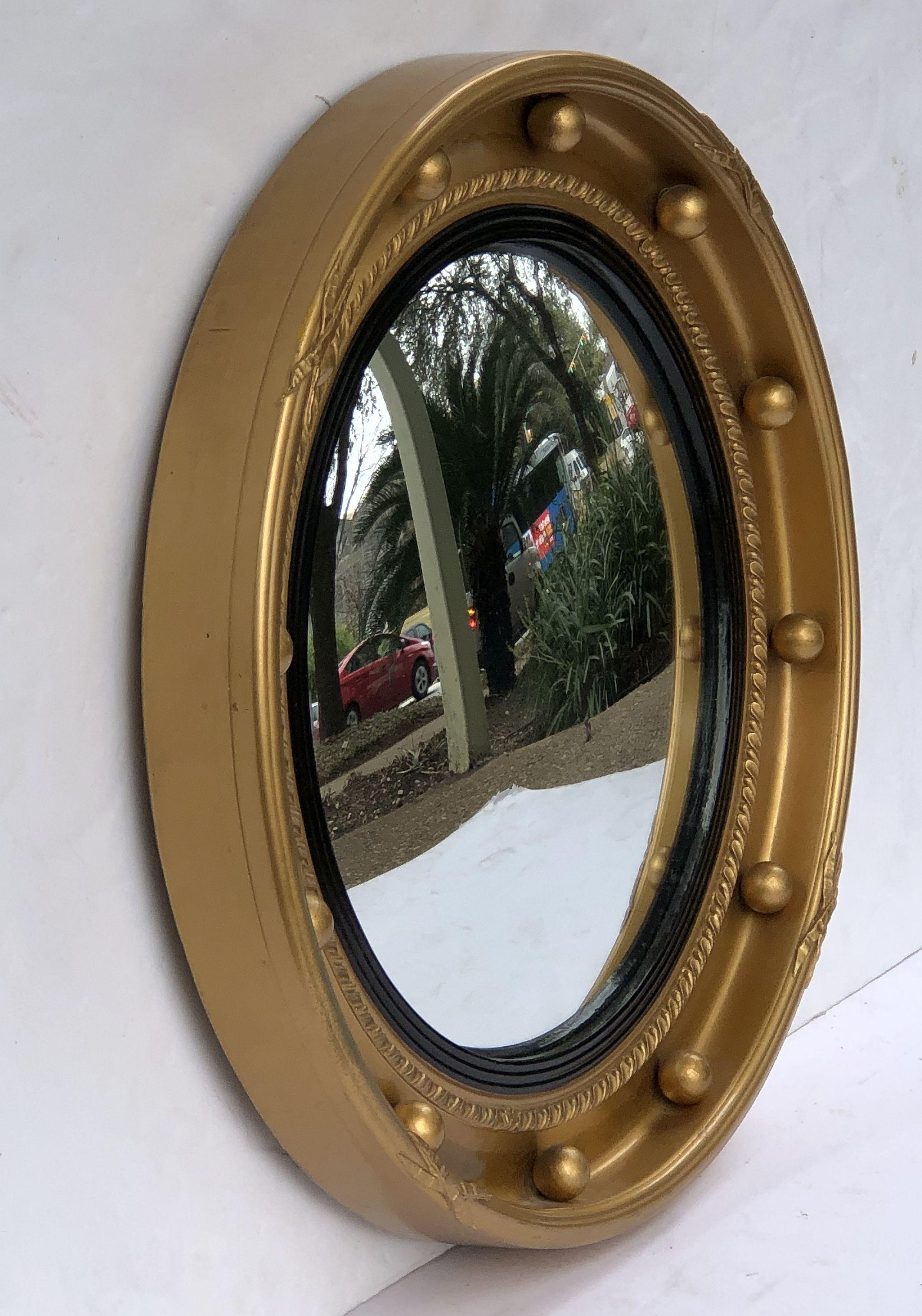 A fine English round or circular convex mirror featuring a Regency design of a moulded gilt frame and ebonized trim, with gilt balls around the circumference.

Dimensions: Diameter 16 inches x depth 1 3/4 inches.
 