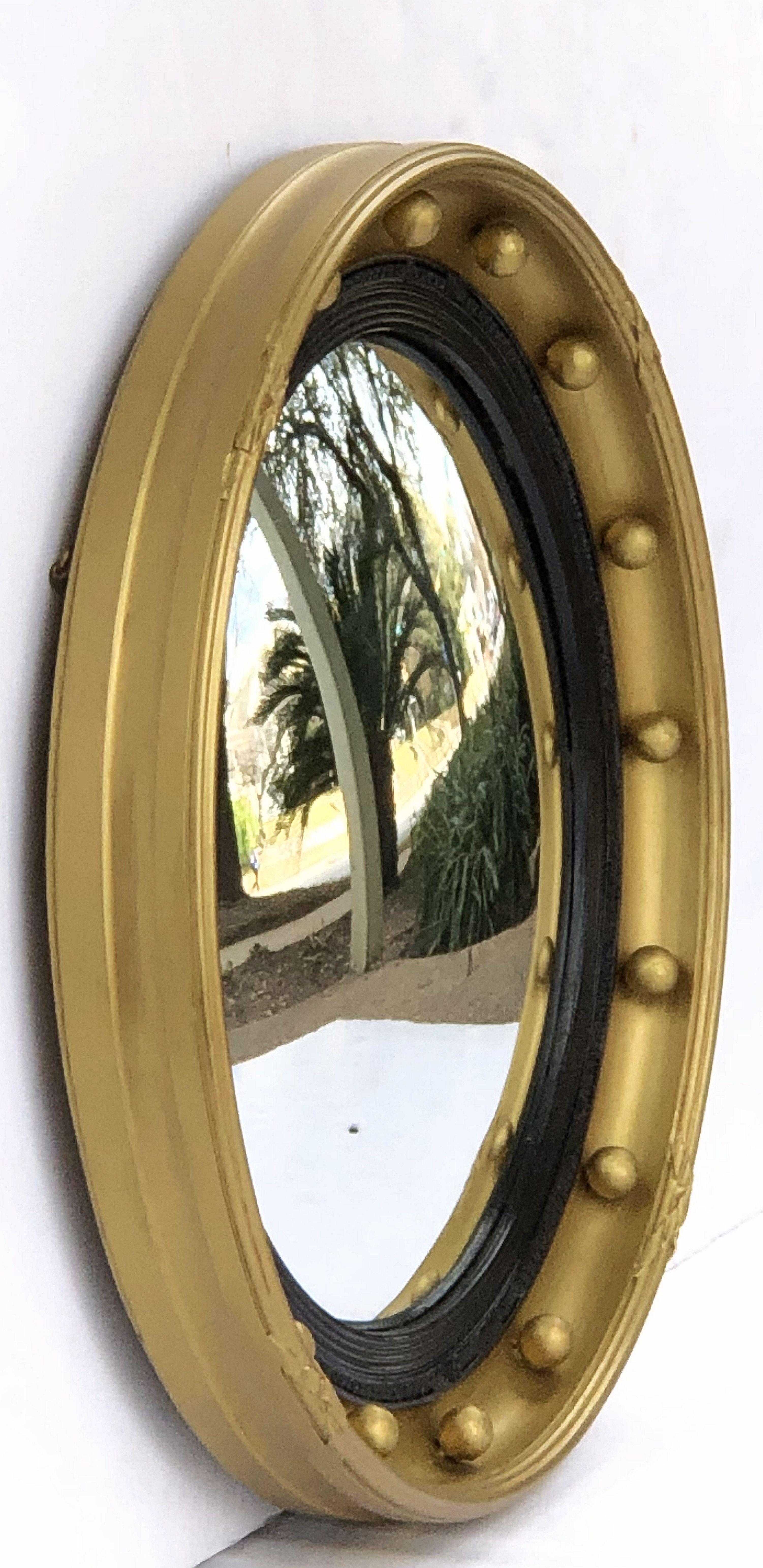 A fine English round or circular convex mirror featuring a Regency design of a moulded gilt frame and ebonized trim, with gilt balls around the circumference.

Dimensions: Diameter 18 3/4 inches x Depth 2 1/4 inches.