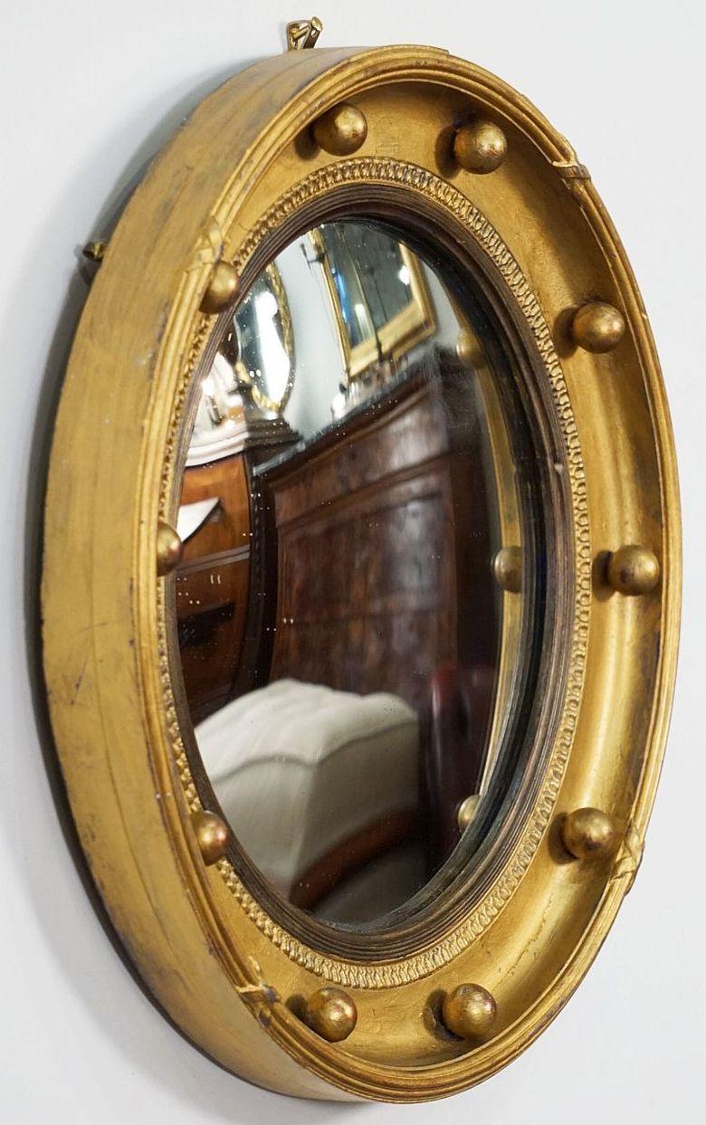 A fine English round or circular convex mirror featuring a Regency design of a moulded gilt frame and ebonized trim, with gilt balls around the circumference.

Dimensions: Diameter 13  3/4 inches x Depth 1 5/8 inches