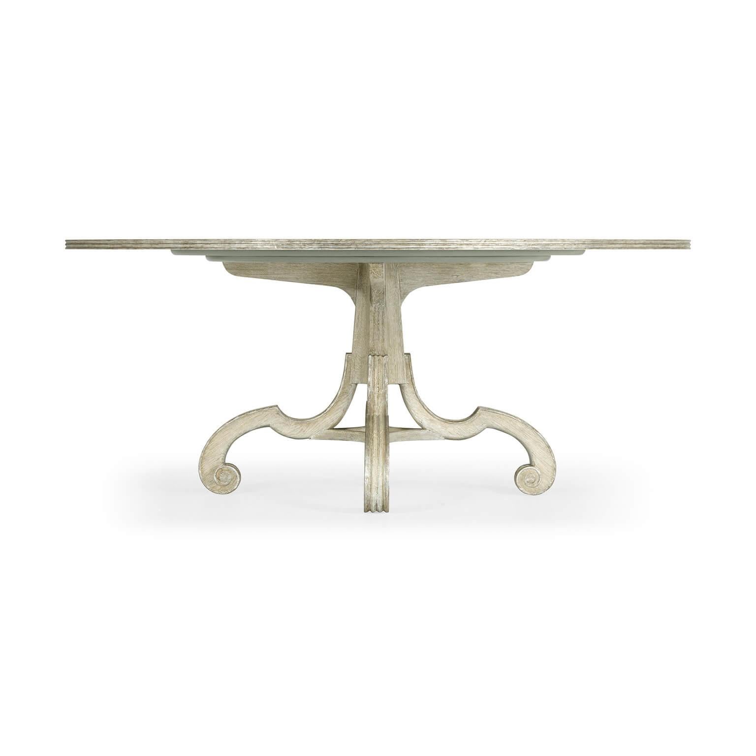 A George II style English Venetian white washed oak round dining table with scroll leg pedestal base and silver gilt edge highlights.

Dimensions: 70.75