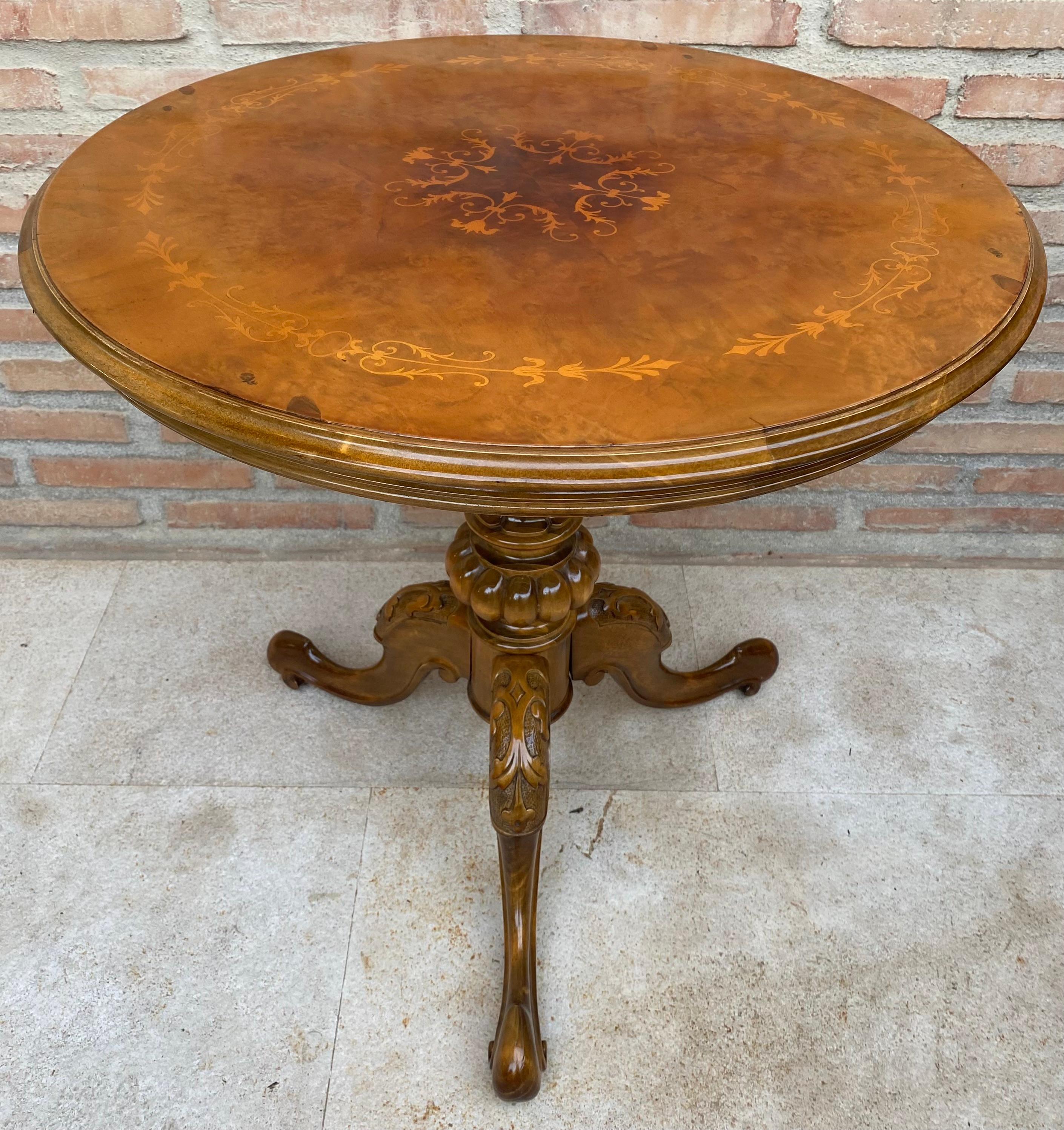 The English tea table is an original piece of furniture made at the end of the 19th century. This round shaped tea table has a marquetry top supported by a carved pedestal with three feet.