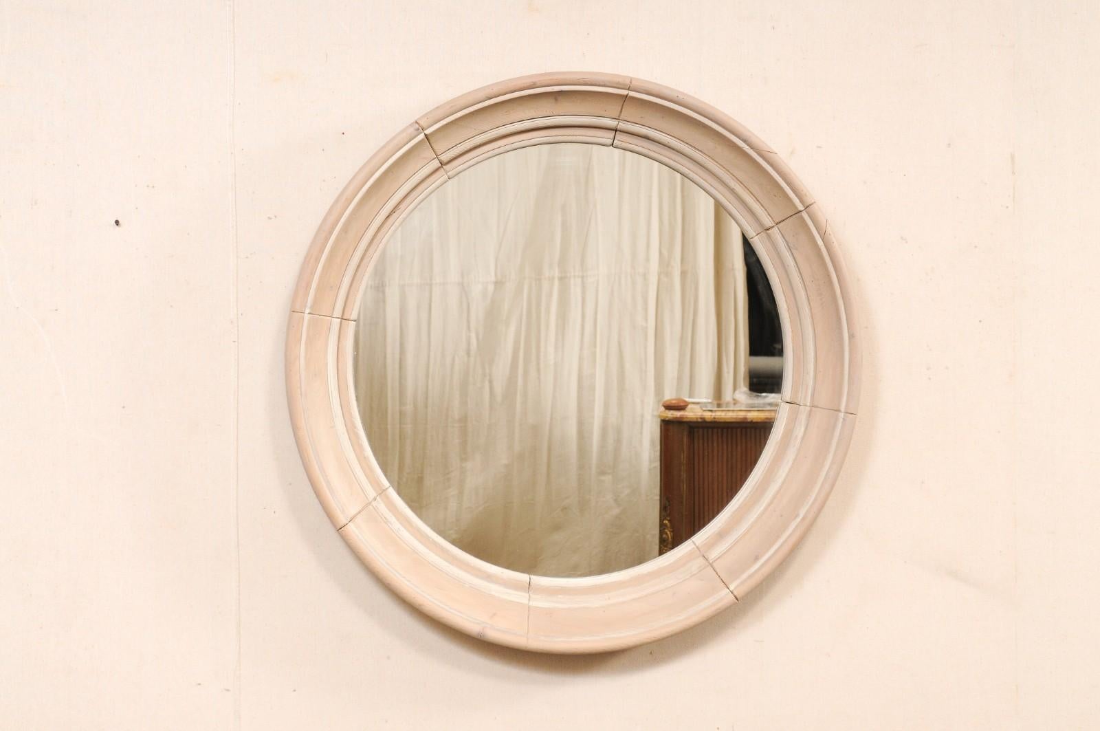 Miroir rond vintage anglais avec encadrement en bois blanchi et peint. Ce miroir d'Angleterre présente un miroir de forme circulaire, entouré d'un cadre en bois de forme ronde. L'entourage est composé de plusieurs pièces lisses et plates à