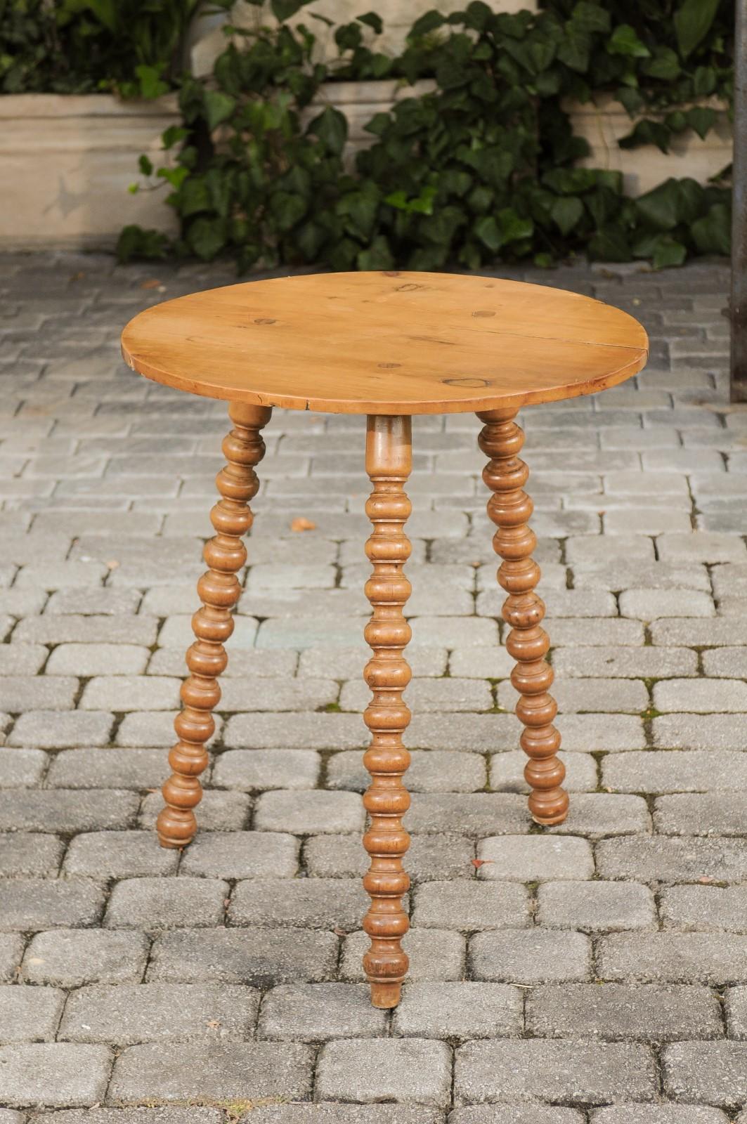 An English pine cricket table from the late 19th century, with bobbin legs and round top. Born in England during the last quarter of the 19th century, this charming cricket table features a circular top sitting above three eye-catching, slightly