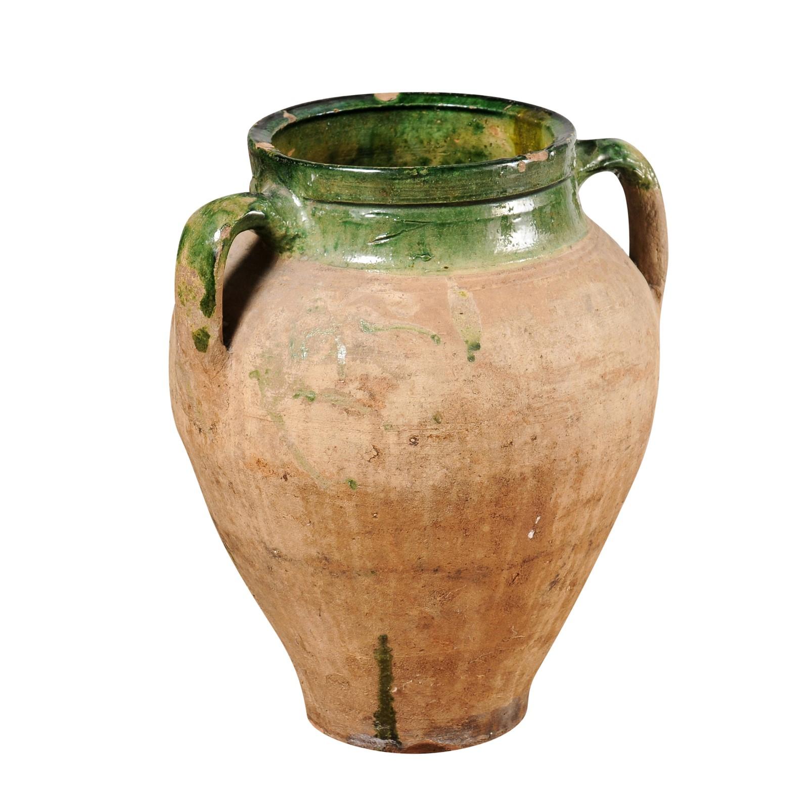 An English terracotta olive oil jar from circa 1930 with green glaze, two handles and rustic character. Discover the rustic elegance of this English terracotta olive oil jar, dating back to circa 1930, a piece steeped in history and character. This