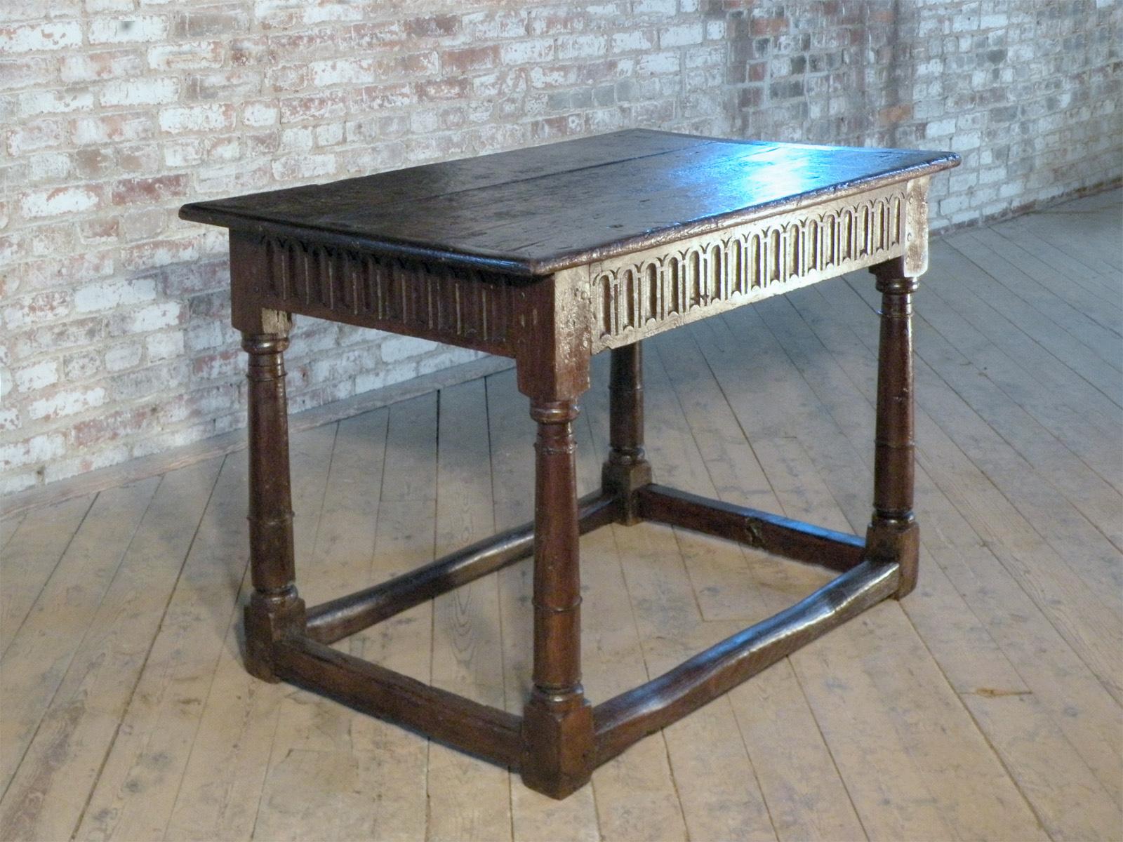 English Late Elizabethan / Charles I Oak Center or End Table. A rare early table, in beautifully worn, rustic condition. Having a three-board top above a carved frieze, supported by columnar legs joined by box stretcher. Solid, pegged construction.