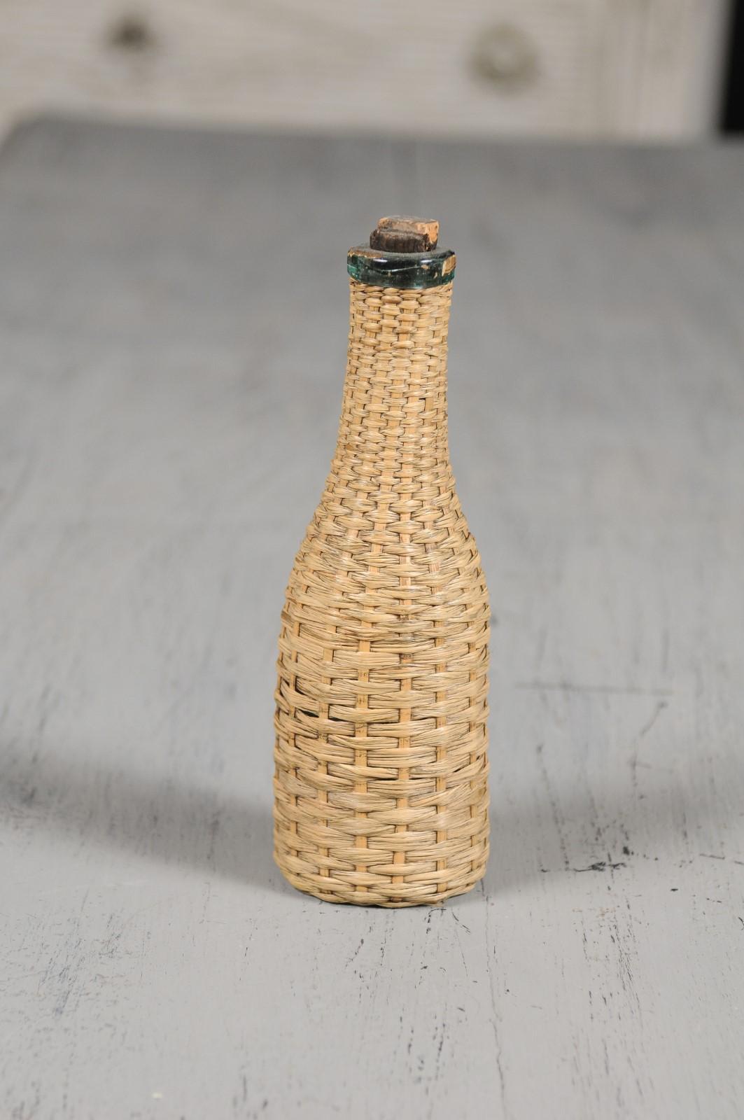 An English straw covered bottle from the 19th century with cork. Charming our eyes with its rustic appearance, this English bottle is covered with straw and presents its nicely weathered cork. Perfect to be placed in a kitchen, a dining room or in a