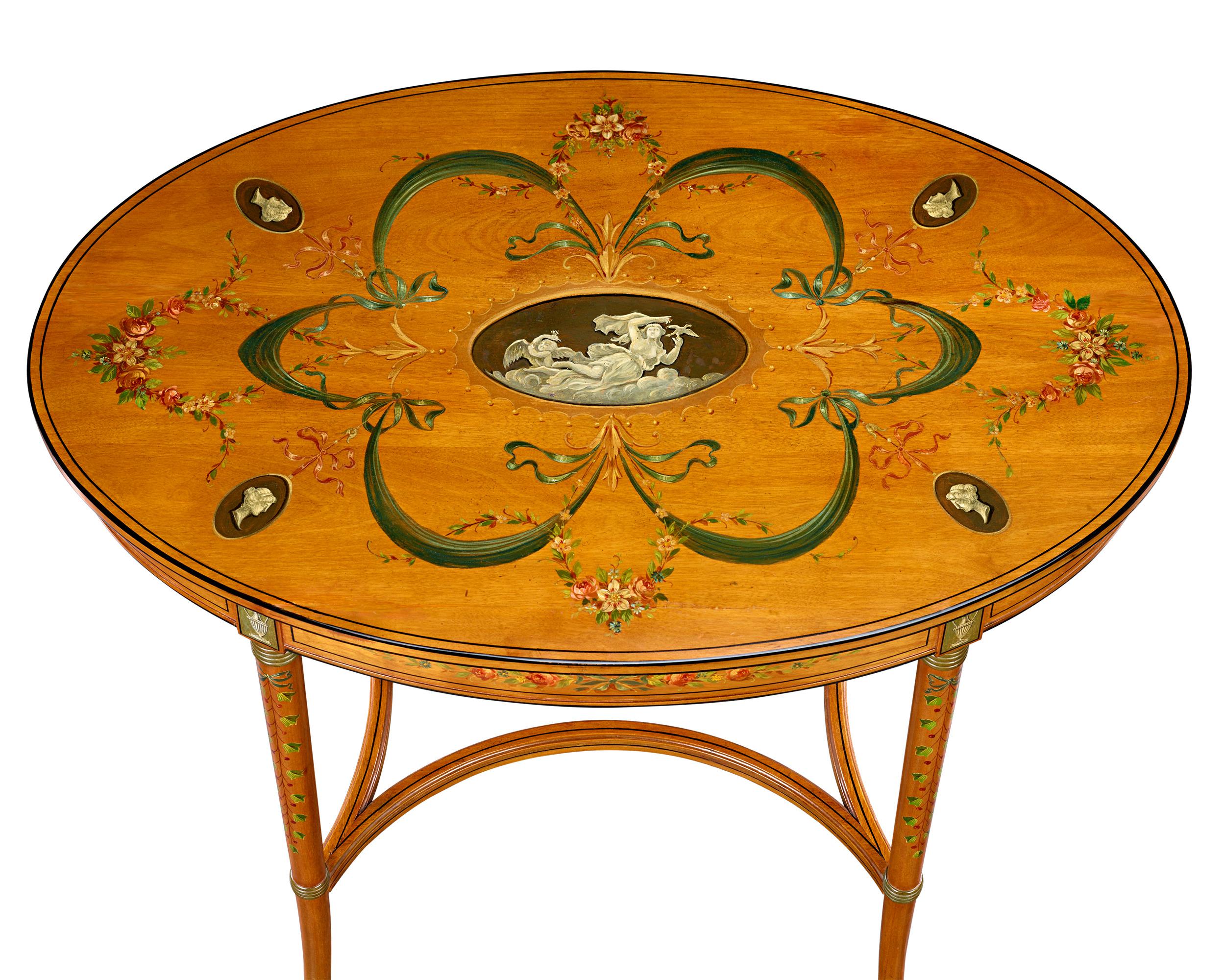 This exquisite pair of hand-painted English satinwood parlor tables is embellished with intricate detailing inspired by floral and classical themes—hallmarks of the esteemed Sheraton Revival style. The fine wood and masterfully delicate natural