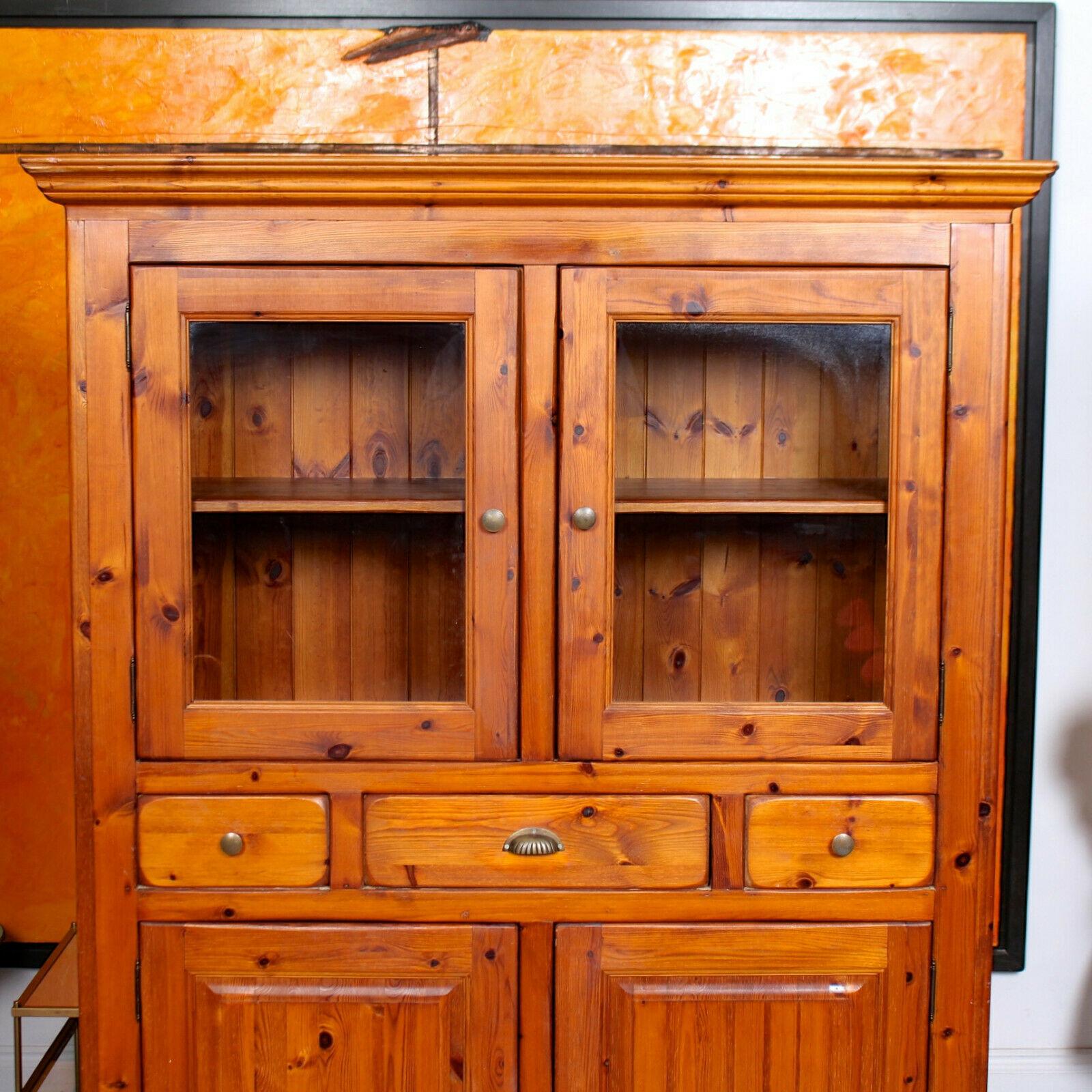The carved cornice above glazed paneled doors enclosed shelving and fitted drawers with dovetailed jointing and tongue and groove solid interiors. Fitted a pair of paneled doors below enclosed shelving and raised on carved feet.