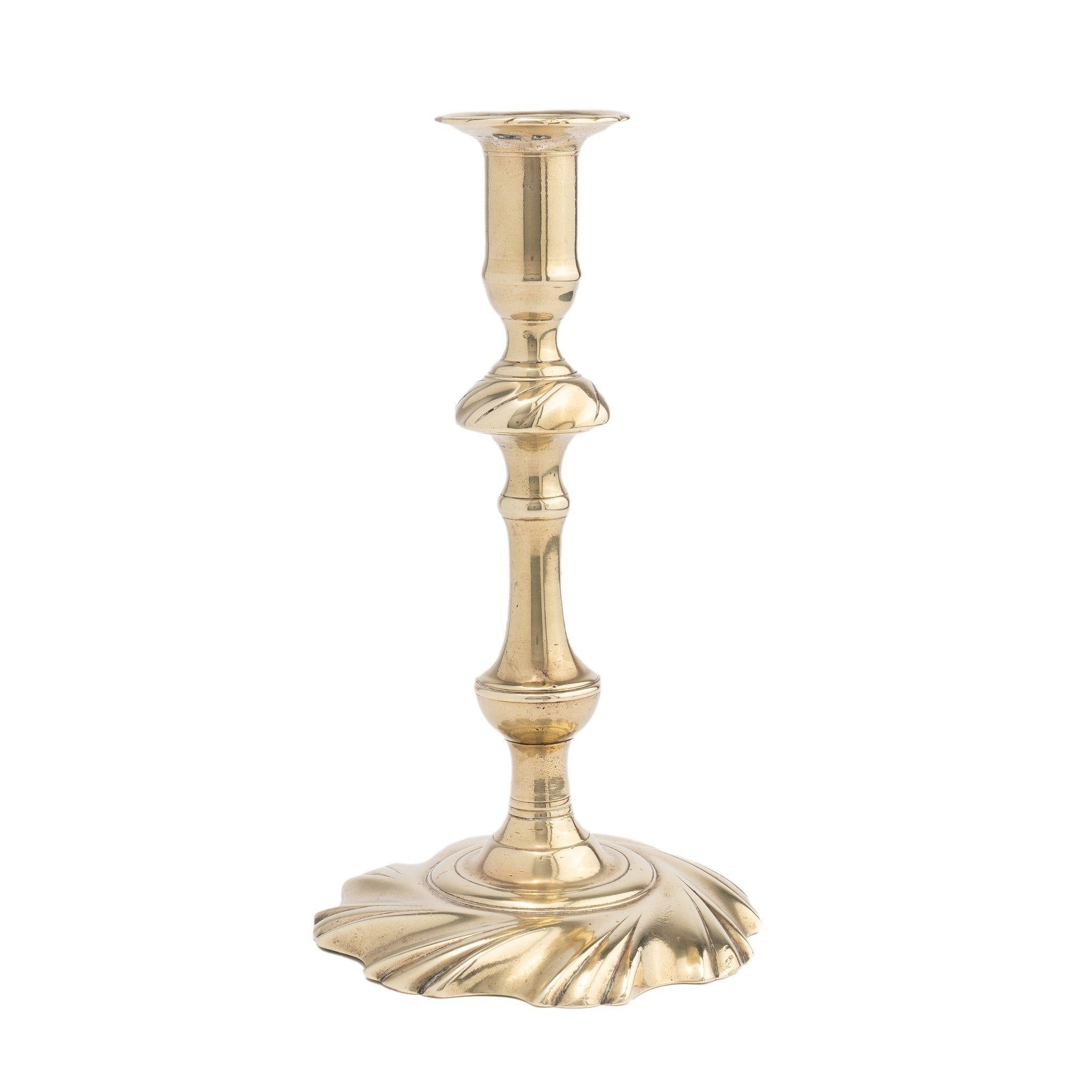 Seam cast brass baluster candlestick which incorporates a swirl cast knob on the candle shaft, and swirl edge on the rim of the bobeshe which is peened to an eight lobed swirl base.

Birmingham, England, circa 1750.