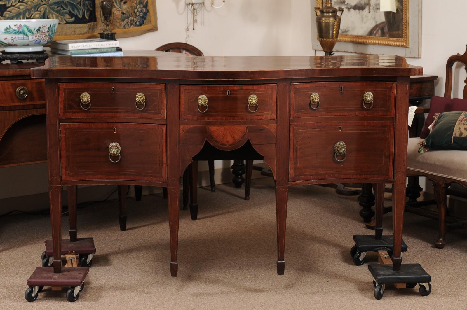 Credenza a serpentina in mogano della metà del XIX secolo con intarsi in legno di bosso e corde ebanizzate, bordatura trasversale e tiretti a testa di leone che terminano su piedi a vanga.
