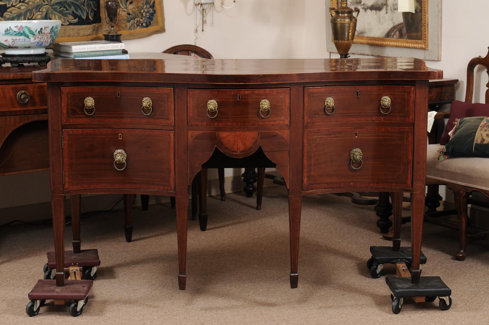 A mid 19th century mahogany serpentine sideboard with boxwood and ebonized string inlay, cross-banding and lion head pulls ending on spade feet.