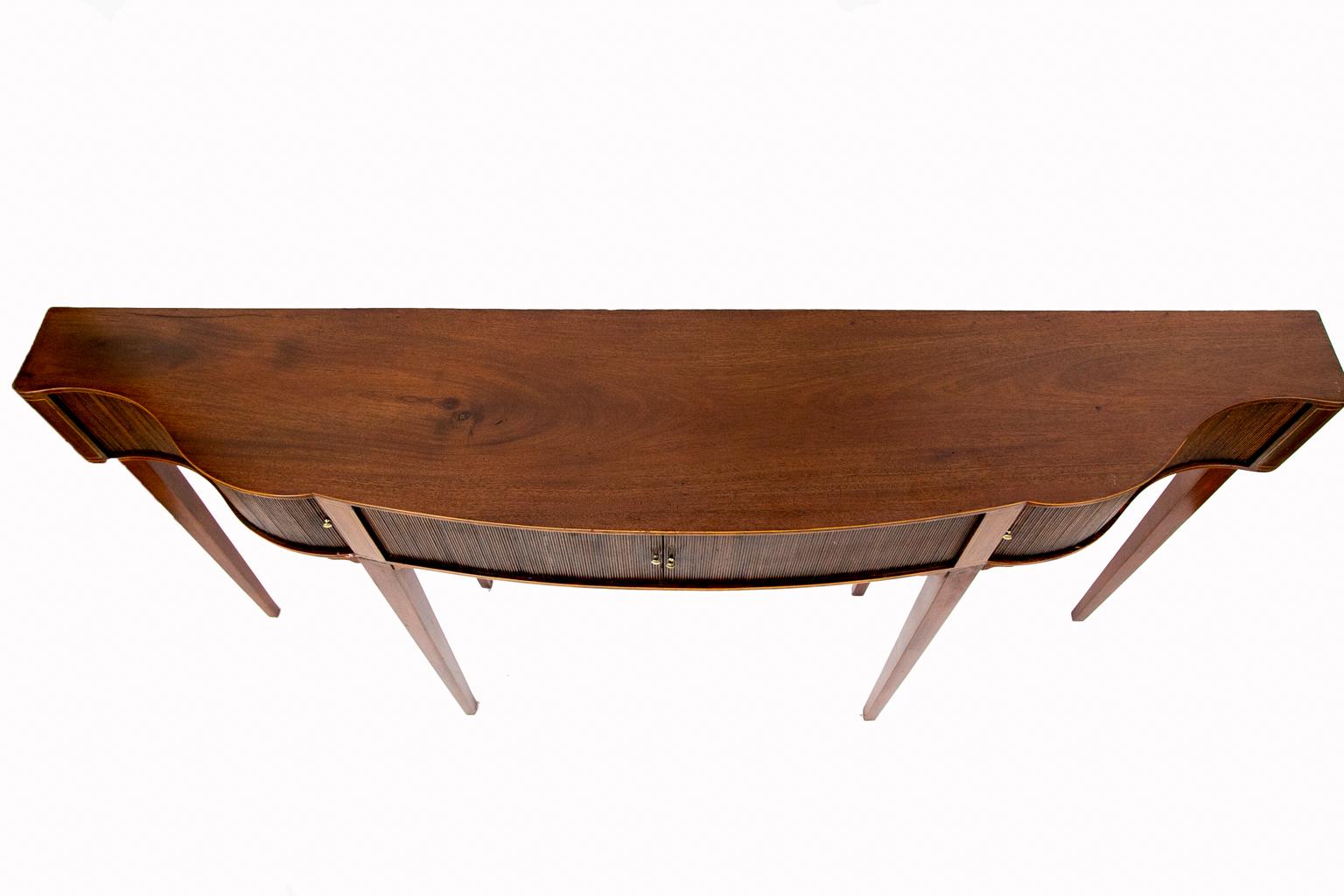 English serpentine tambour console table, with the top edge double boxwood cross banded. The center dividing stiles have boxwood and rosewood string inlay. The rounded corners have boxwood string inlay, and the double string crossbanding on the top