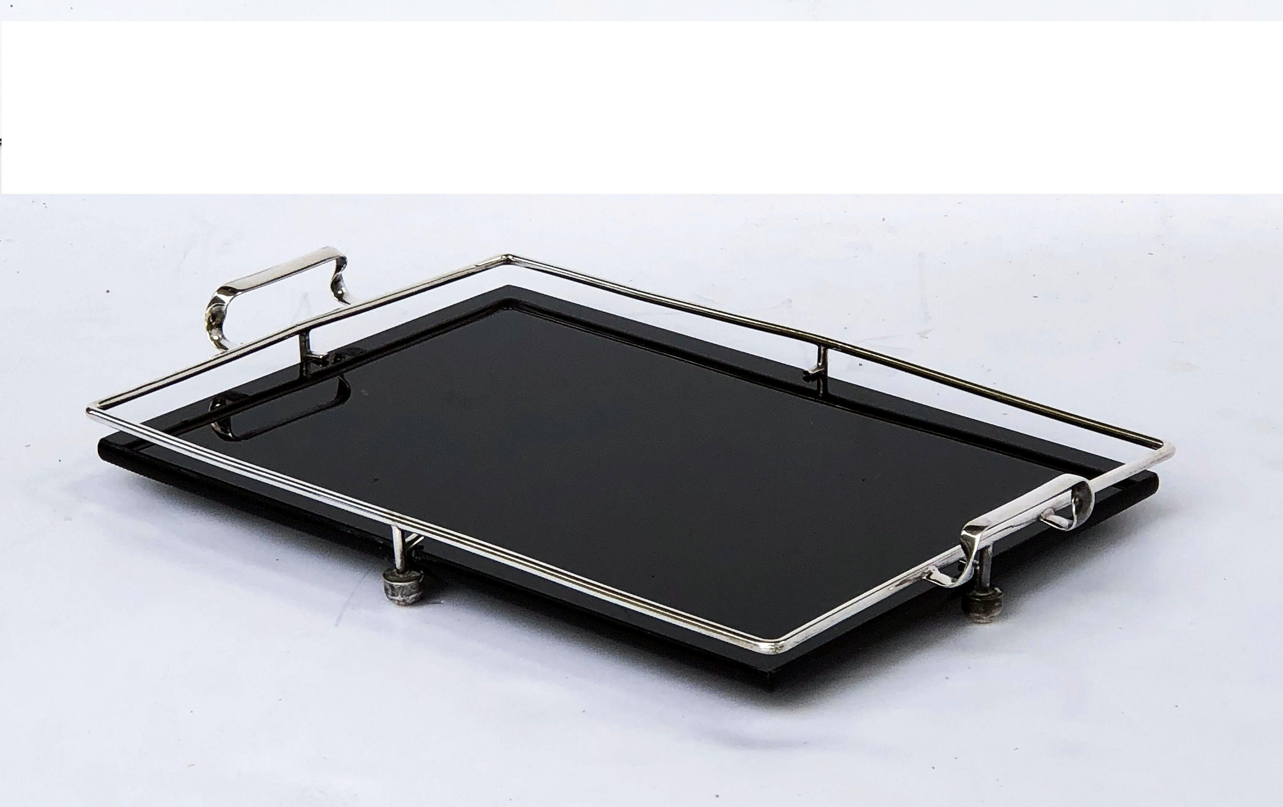 A fine English rectangular serving tray from the Art Deco period, featuring a rectangular black or ebony glass mounted to a stylish chrome metal frame with opposing handles and round feet.