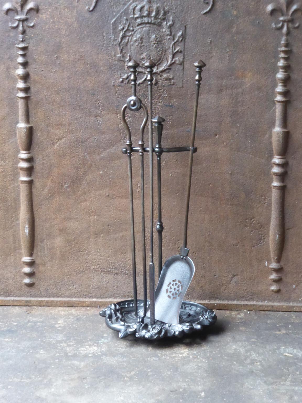 English set of three wrought iron fireplace tools with a stand made of wrought iron and cast iron. The fire tool set is in a good condition and is fully functional, 19th century, Victorian.