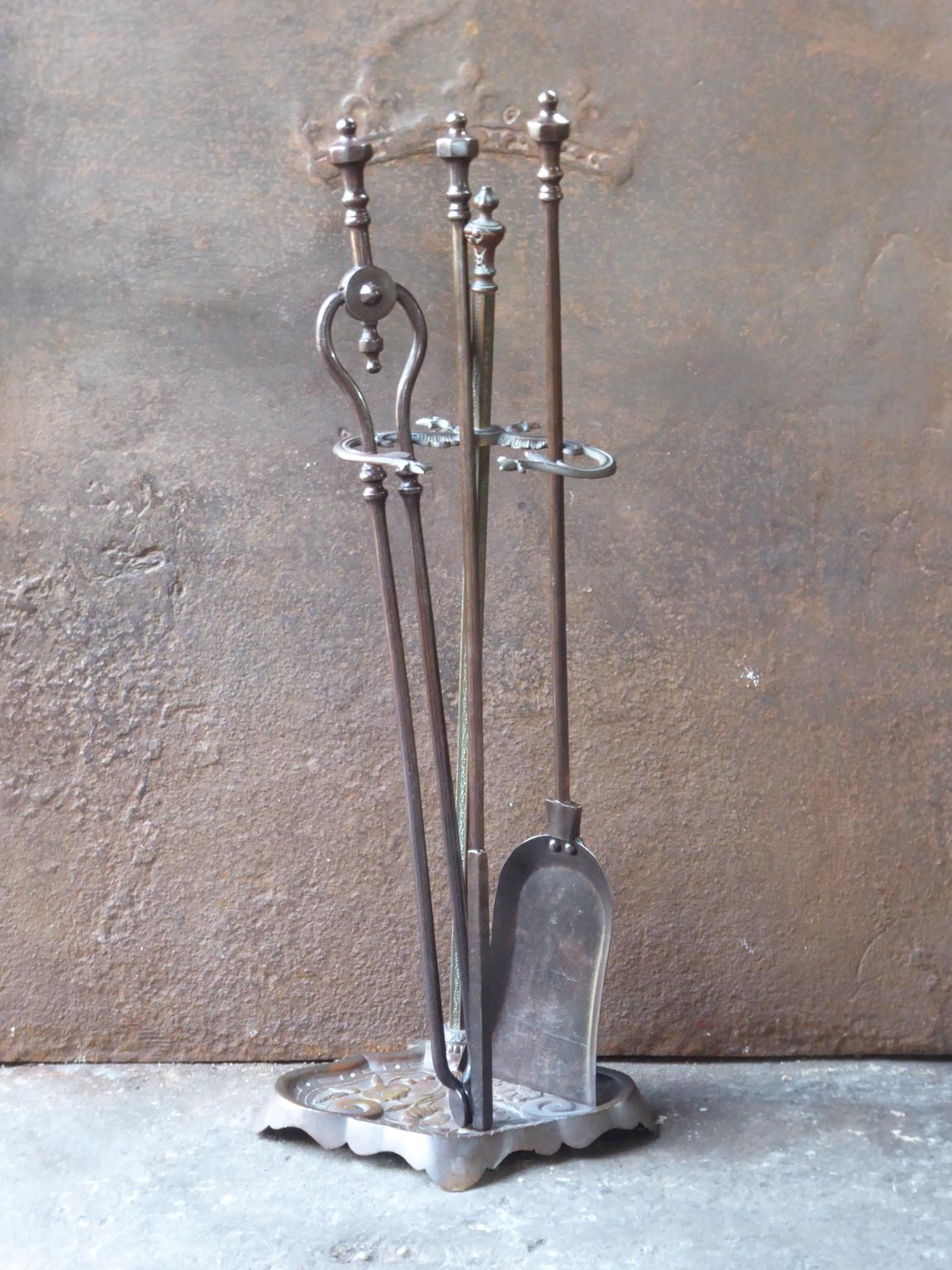 English set of three fireplace tools with a stand made of wrought iron and brass. The fire tool set is in a good condition and is fully functional. 19th century, Victorian.