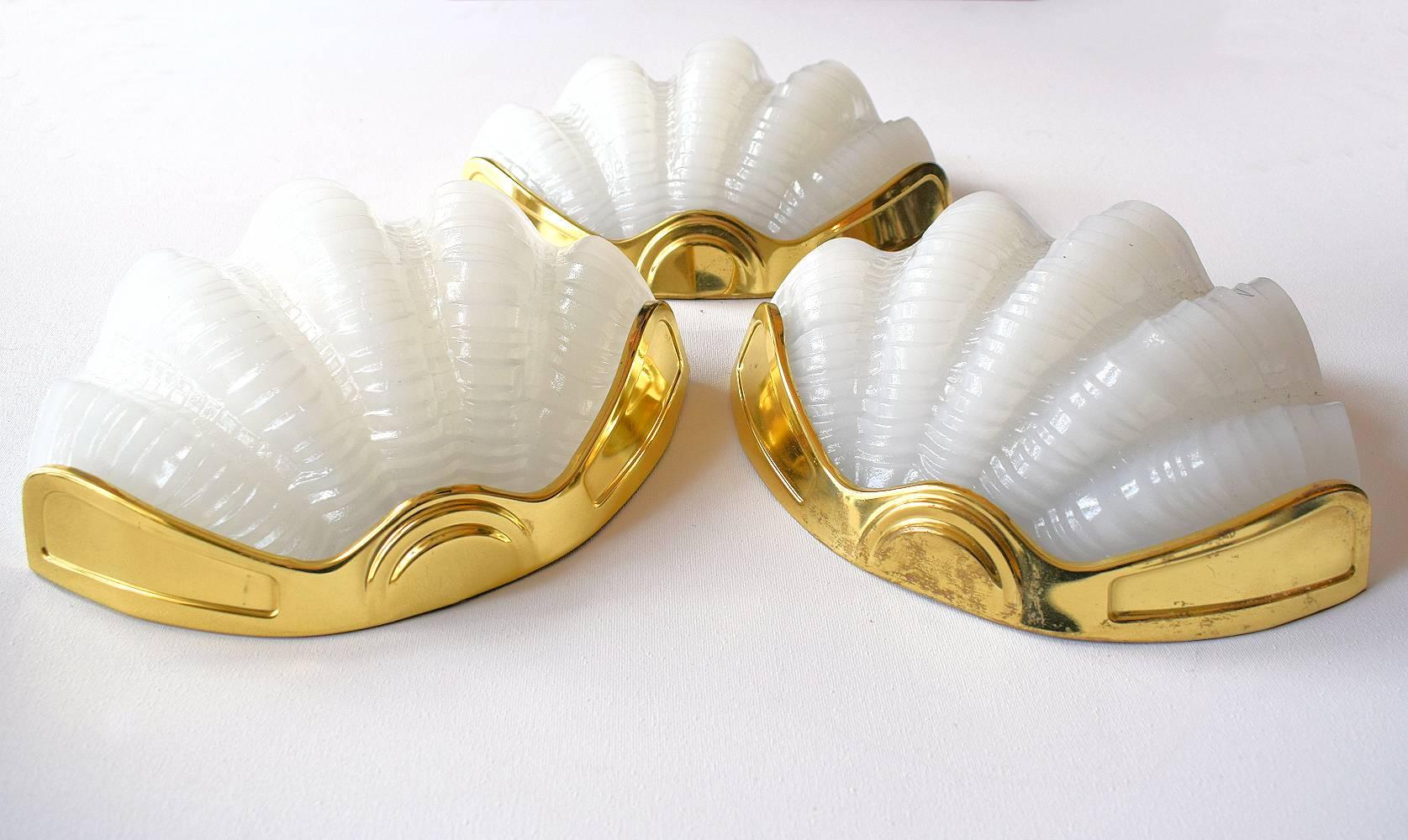 A beautiful matching set of four 1930s Art Deco wall lights of shell form. The gilt frames are in very good original condition which when fitted to the wall hold the beautiful soft milk white opaque glass shades firmly in place. Truly beautiful and