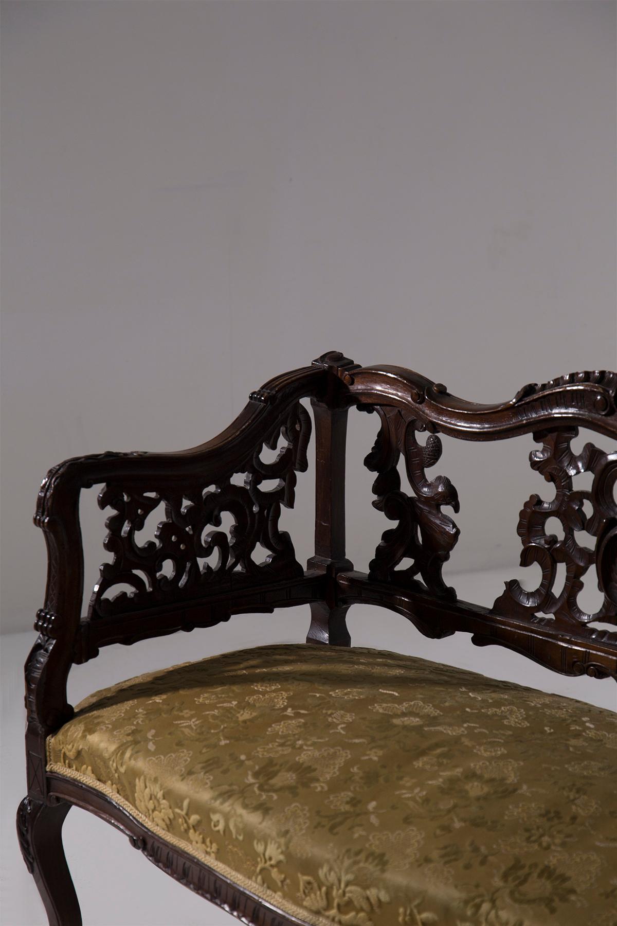 Este elegante loveseat inglés, de refinado estilo Art Nouveau, es un verdadero testimonio del gusto y la artesanía de finales del siglo XIX y principios del XX. Los dos asientos están enmarcados por una estructura de madera ricamente tallada, que se