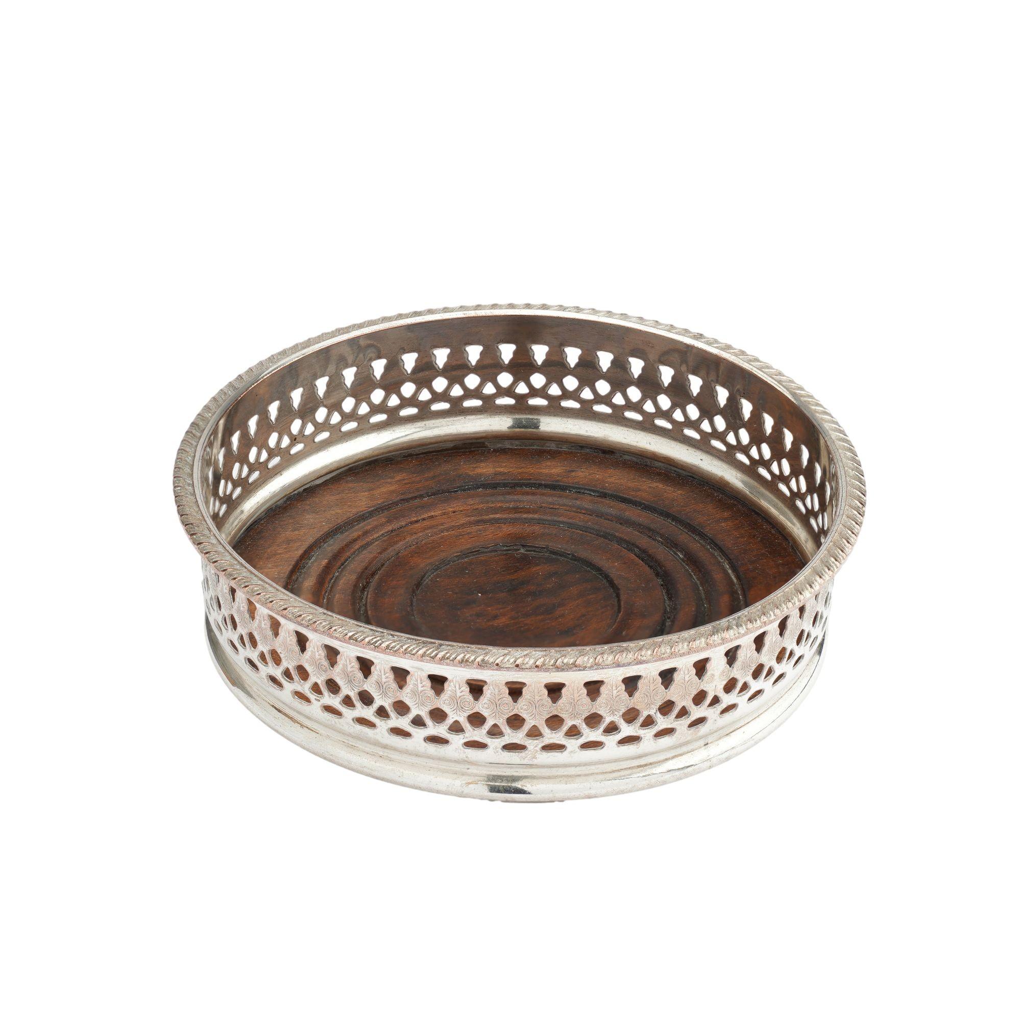 Sterling silver on copper Sheffield decanter coaster. The coaster is stamped with a Neoclassic anthemion decoration on the pierced gallery below a gadroon molding. A turned wood base is fitted to the bottom of the coaster.

Sheffield, England, circa