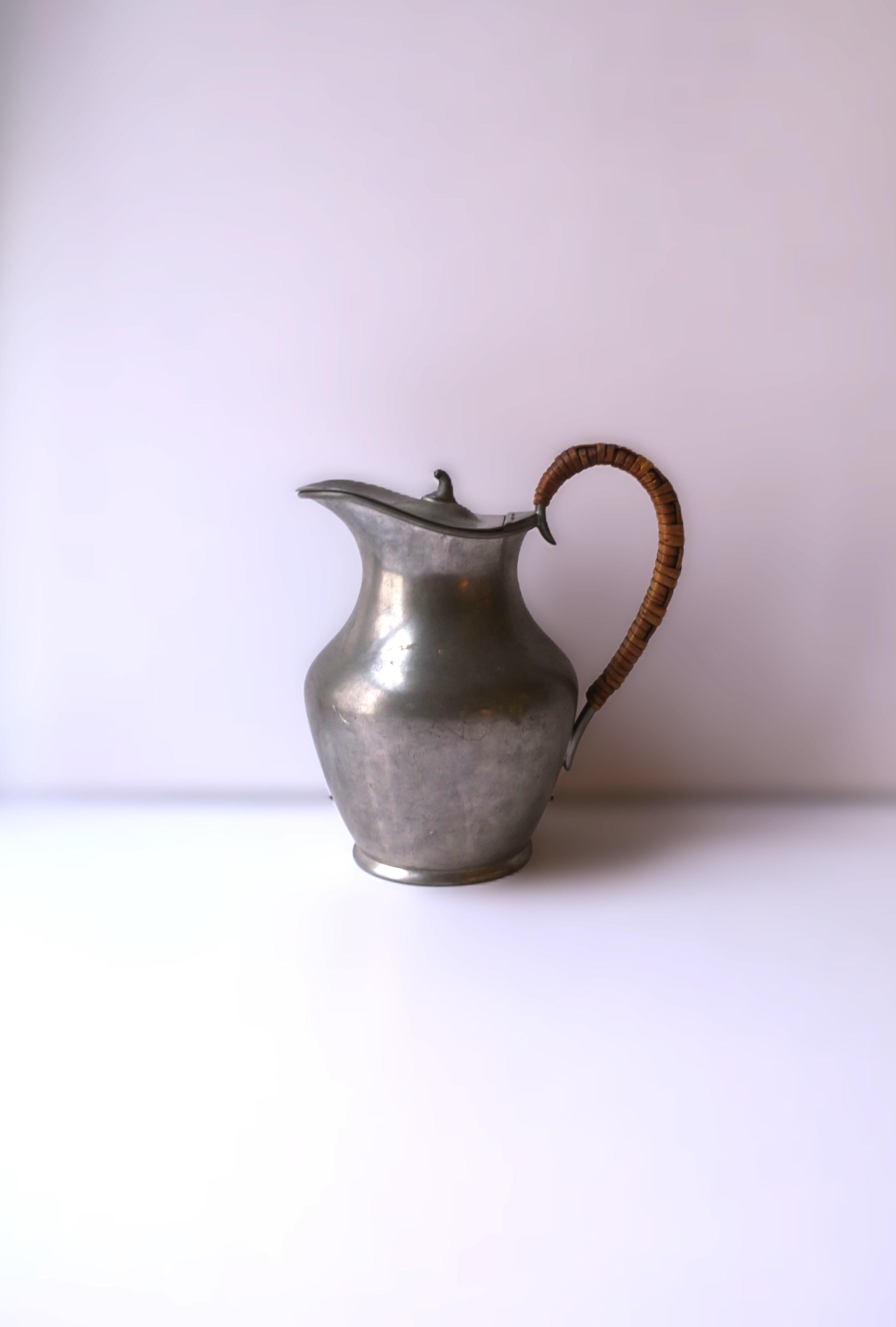 An English Sheffield pewter pitcher with flip-black lid and wicker handle, circa early-20th century, England. With markers' mark and origin on bottom underside as shown in last images. A great piece for a kitchen shelf, cabinet, table, etc.
