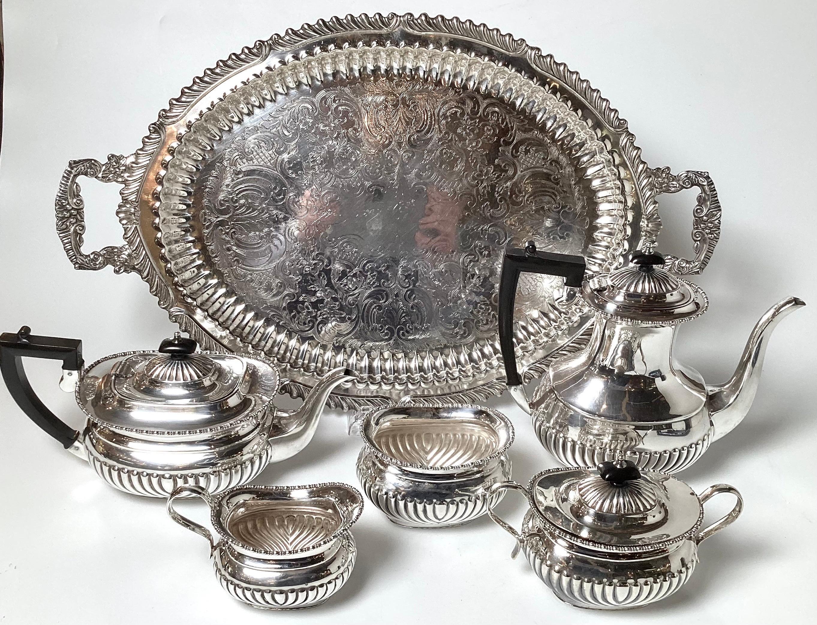 A classic old world Queen Anne Patterned Sheffield plate tea and coffee service including coffee pot, tea pot, sugar bowl, creamer and waste bowl.  The perfectly matched tray was added.  All made in England, the entire set measures 25.5 handle to