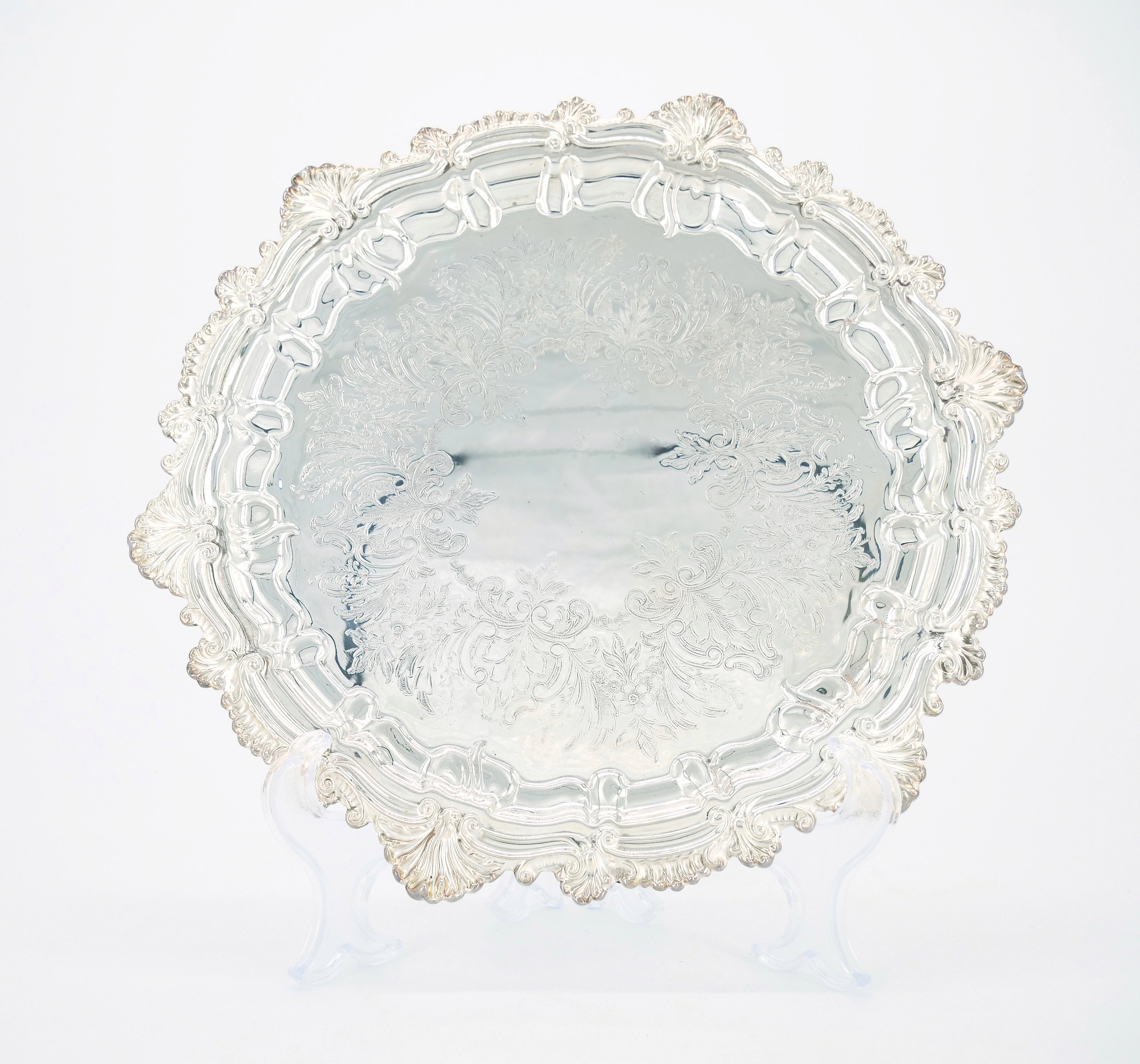 Introduce a touch of timeless elegance to your entertaining with this exquisite English Sheffield Silver Plate serving tray. The round shape is adorned with delicately engraved floral design details on the interior, creating a sophisticated and