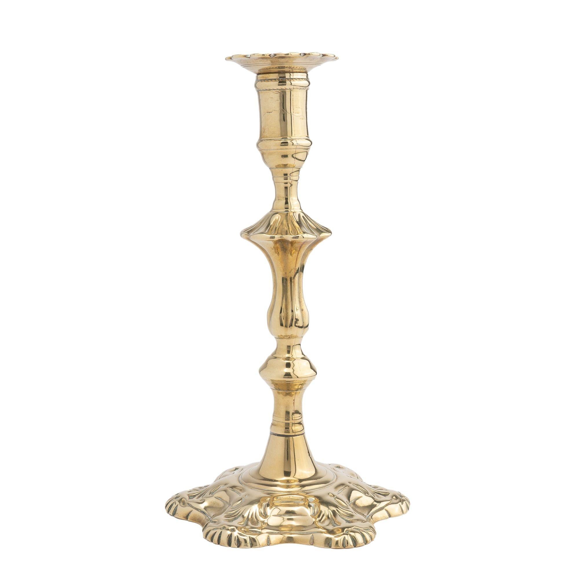 Queen Anne seam cast brass candlestick. The candlestick features a removable scolloped edge bobeshe on an urn form candle cup with waisted stem, which flows into a suppressed ruffled knob on a fluted, extended tulip form shaft over a suppressed