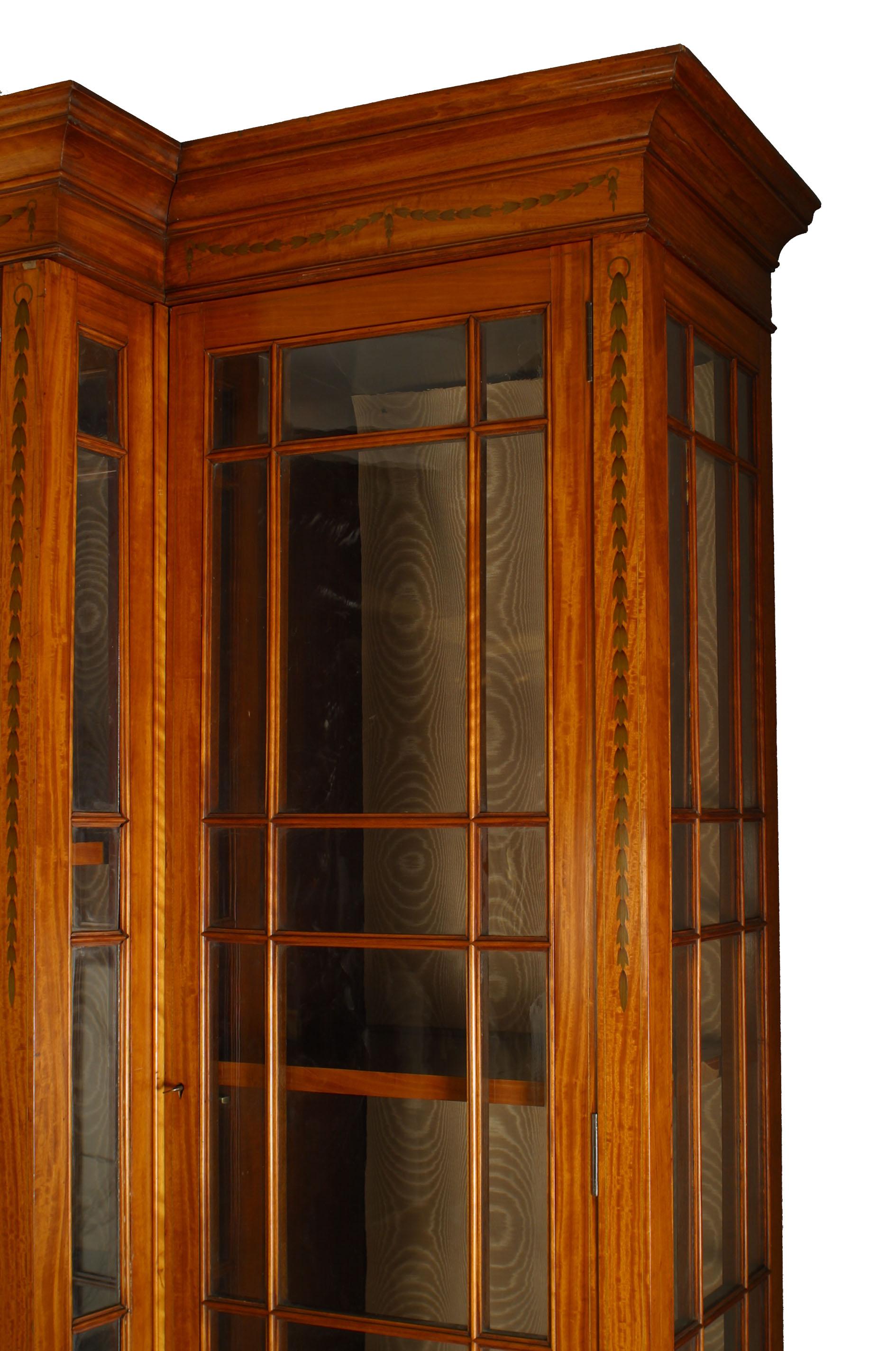 Mueble inglés de estilo Sheraton del siglo XIX, de madera satinada, con puertas y laterales enrejados y incrustaciones de festón y molduras, con 14 estantes.