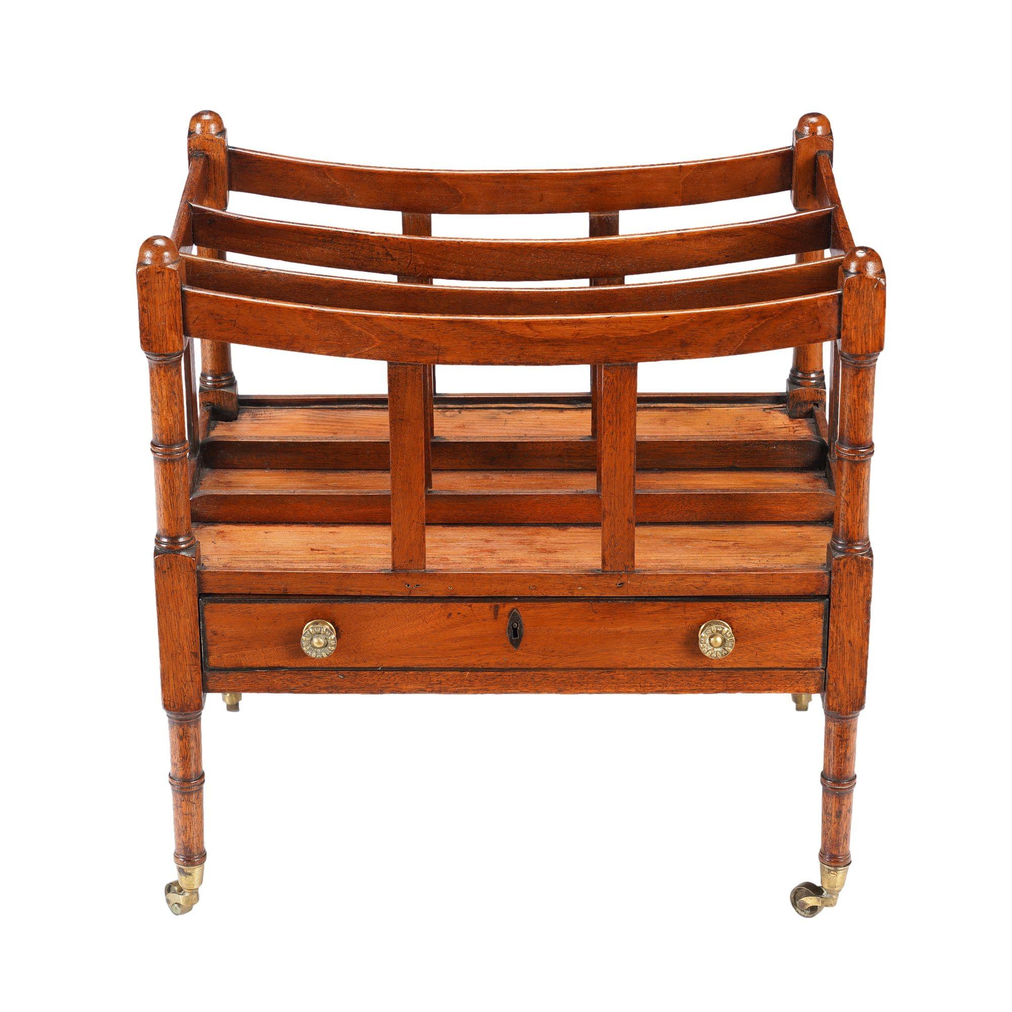 Mahogany Canterbury with bamboo turned legs on cast brass cup castors. The Canterbury features three slatted divisions on turned supports, and a long frieze drawer below the book rack is fitted with its original stamped brass drawer pulls.

England,