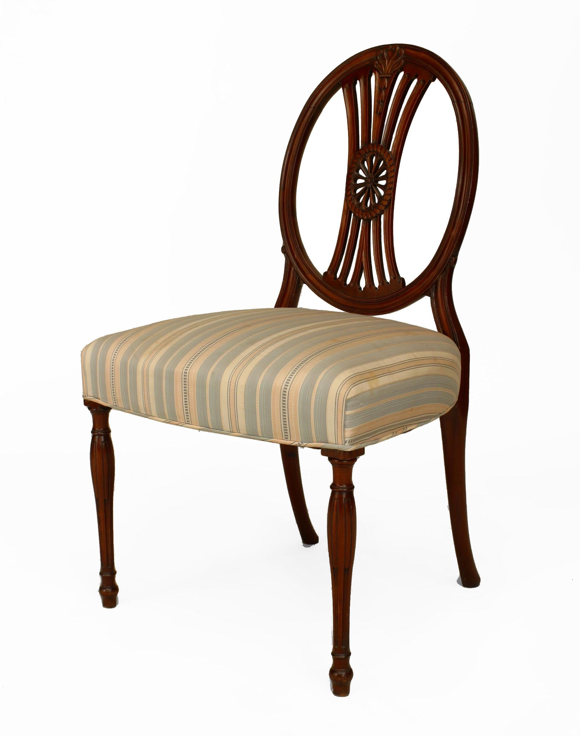 Set of 7 English Sheraton style (20th Century) mahogany chairs with an oval open back with a carved center medallion and fluted tapered legs. Sides: 21½