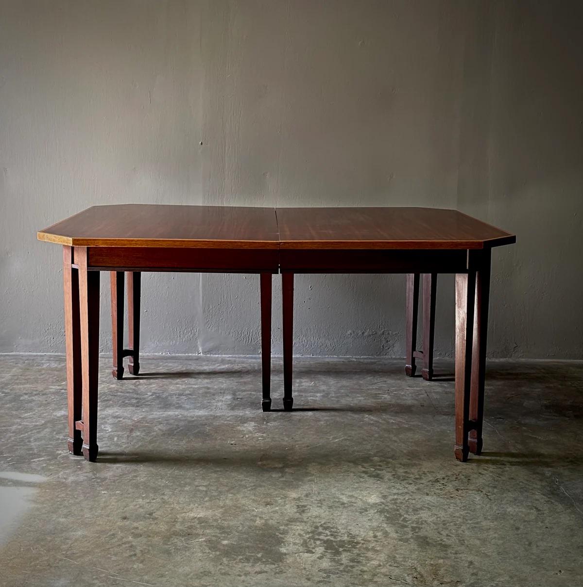 This mahogany table showcases the elegant Sheraton style with its minimalist and restrained design, featuring five extending leaves, string banding, canted corners, and slim tapered double-pronged legs. This piece combines functional versatility