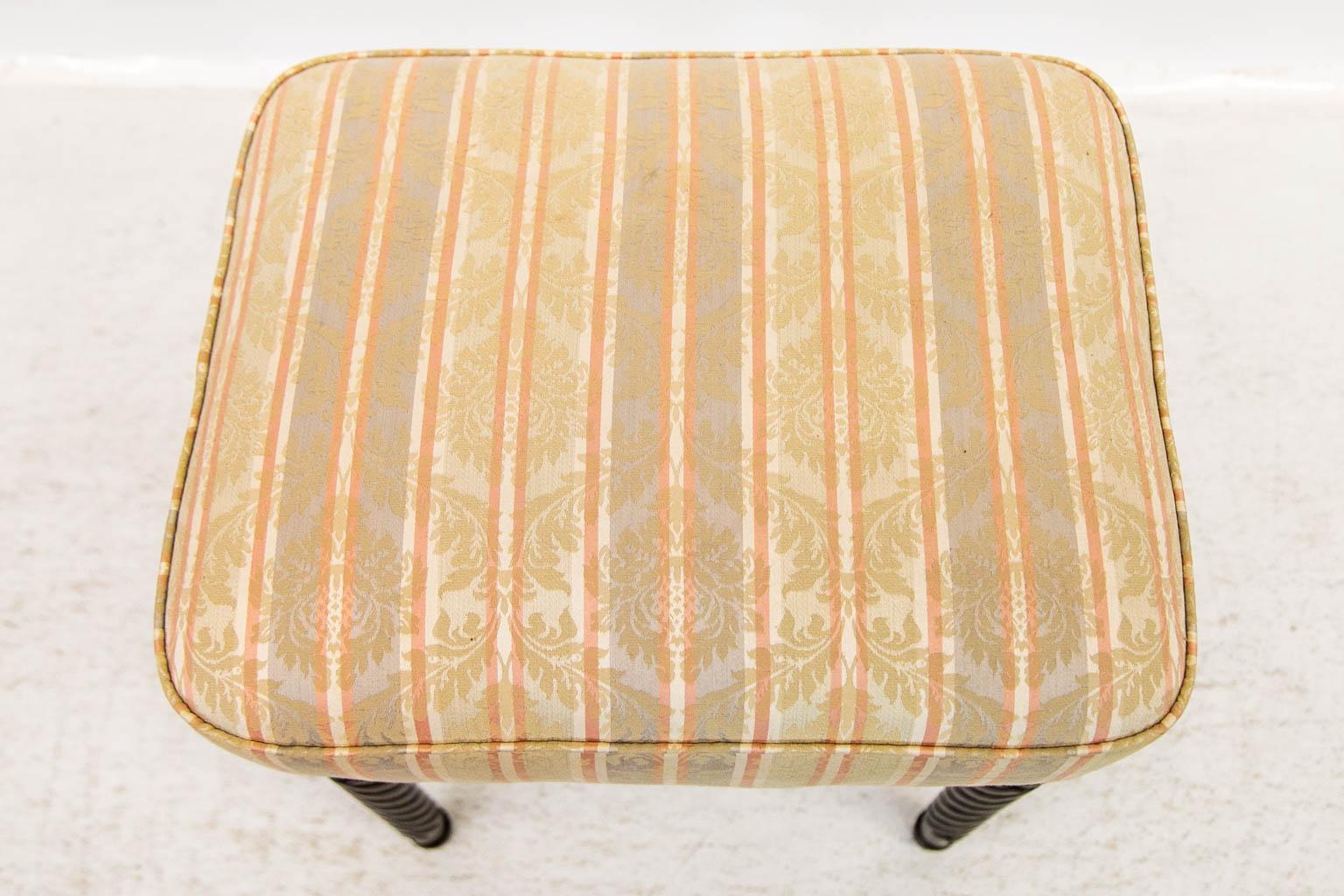 The legs of this stool are turned and have spiraled reeding. The upholstery has been recently renewed and is in good condition.