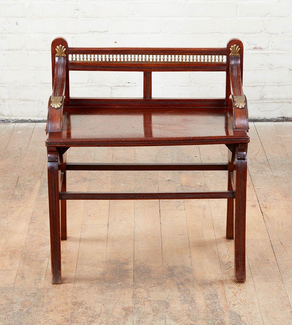 A fine late 19th Century hall bench attributed to James Shoolbred and Co., the rectangular seat with pierced rectangular back with pierced baluster gallery, flanked on each side by downswept arms on circular supports, on rectangular tapering sabre