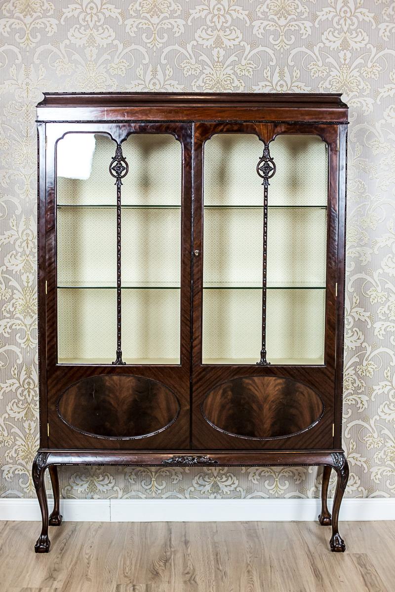 We present you this high showcase from the 19th century in mahogany veneer. This article of furniture is two-door, of a lightweight construction, and is supported on cabriole legs that end with spheres in the bird talons. The showcase is glazed in