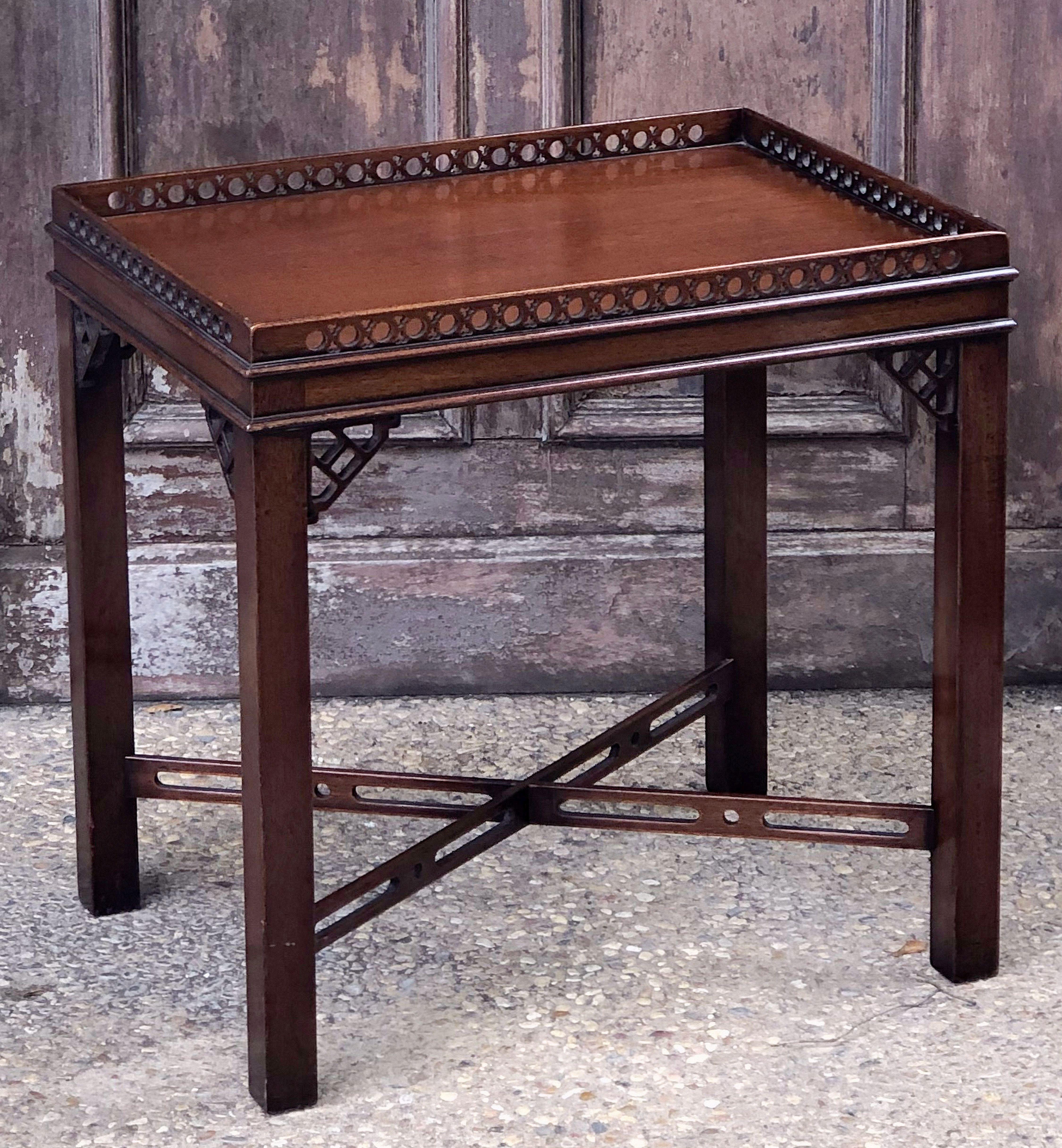 A fine English side, occasional, or end table of mahogany in the Chippendale style, featuring a rectangular carved or pierced gallery rail top over a frieze of four straight legs, braced with crossbar stretcher and decorative fretwork corner