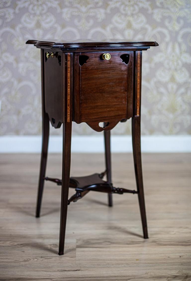 We present you this piece of furniture in the type of a mahogany side table or a nightstand.
All is dated the turn of the 19th and 20th centuries.
There are brass handles on four sides of the apron.
Each side has a round indentation on the