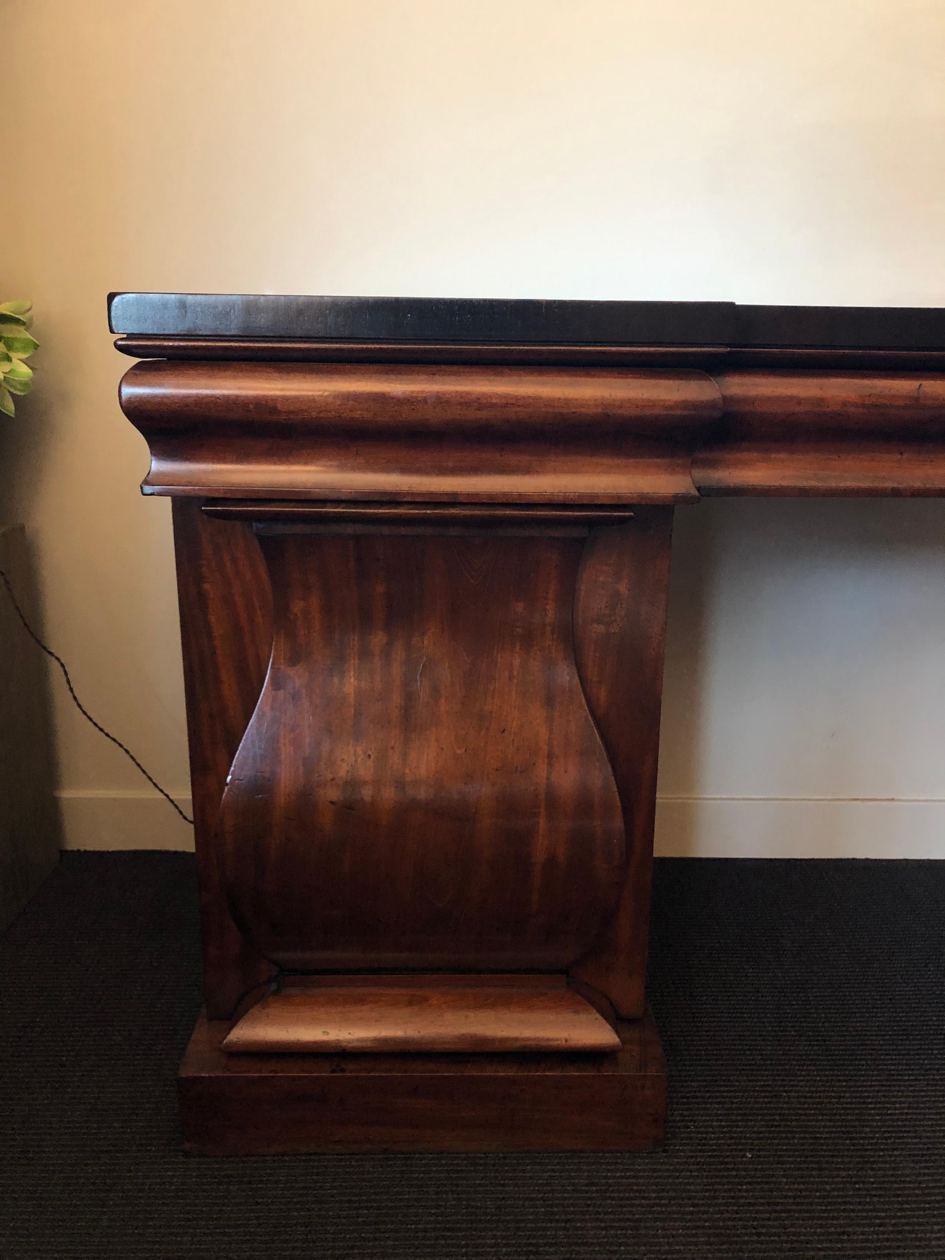English 19th-century architectural mahogany sideboard. Stately and functional, this Victorian piece could also work as a serving table or credenza. A shaped upper frieze conceals drawers above pedestal plinth side cabinets with concealed interior