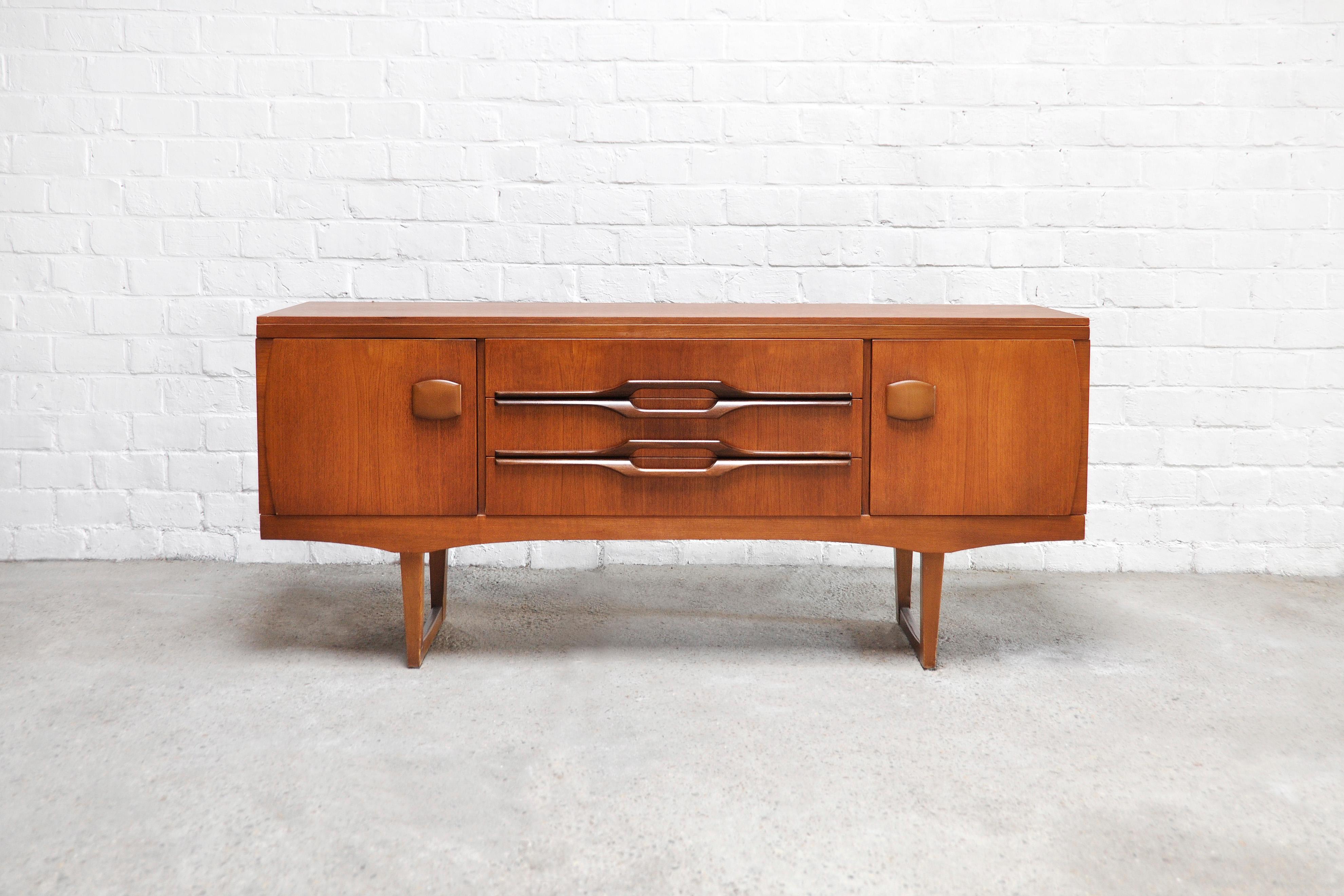 Vintage teak sideboard made by British manufacturer ‘Stonehill Furniture’ as part of their ‘Concord’ Range. The sideboard is finished in a rich-toned teak veneer with solid beechwood legs and lozenge-shaped wooden handles. The middle drawers can be