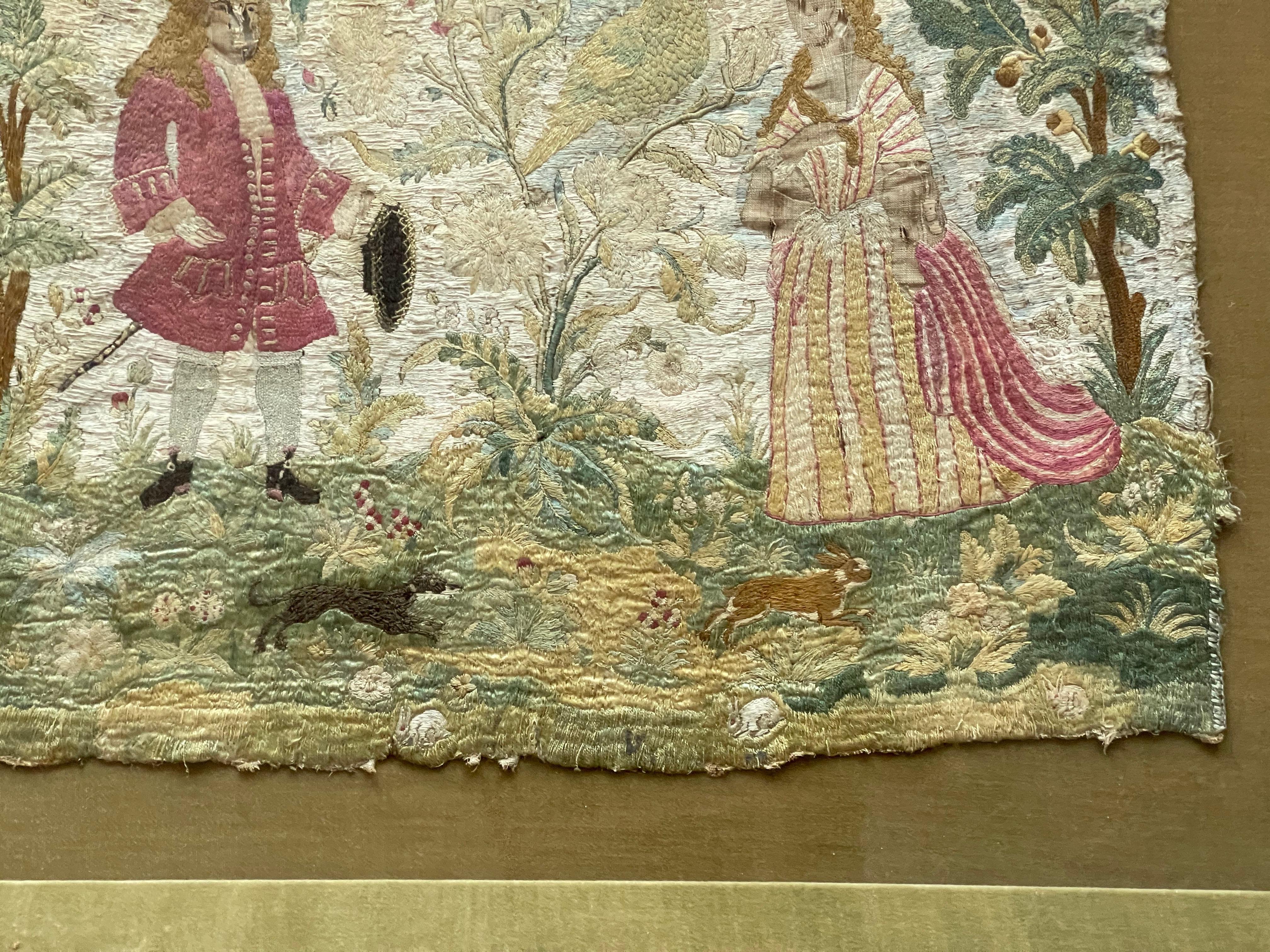 Silk needlework, English, 18th century, with two figures, birds, and animals set in a shadowbox frame.