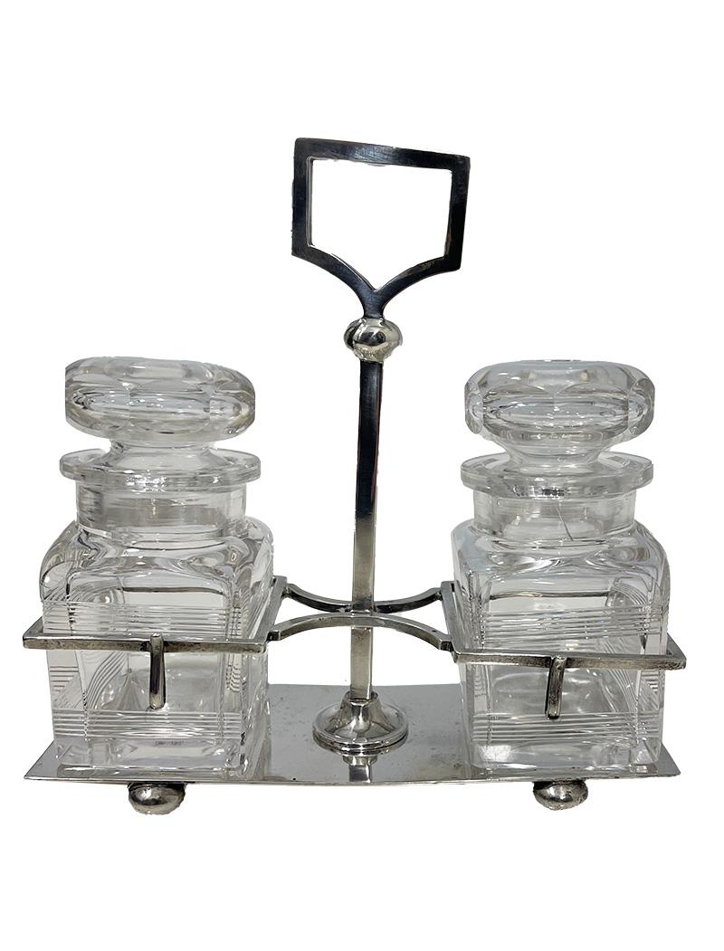 English silver and crystal jam holder by William Hutton & Son Ltd, 1916

A silver holder with two crystal jars with lids. The square crystal jar has two ribbed lines on the side. One lid has a crack in the crystal of the lid. There are two hooks on