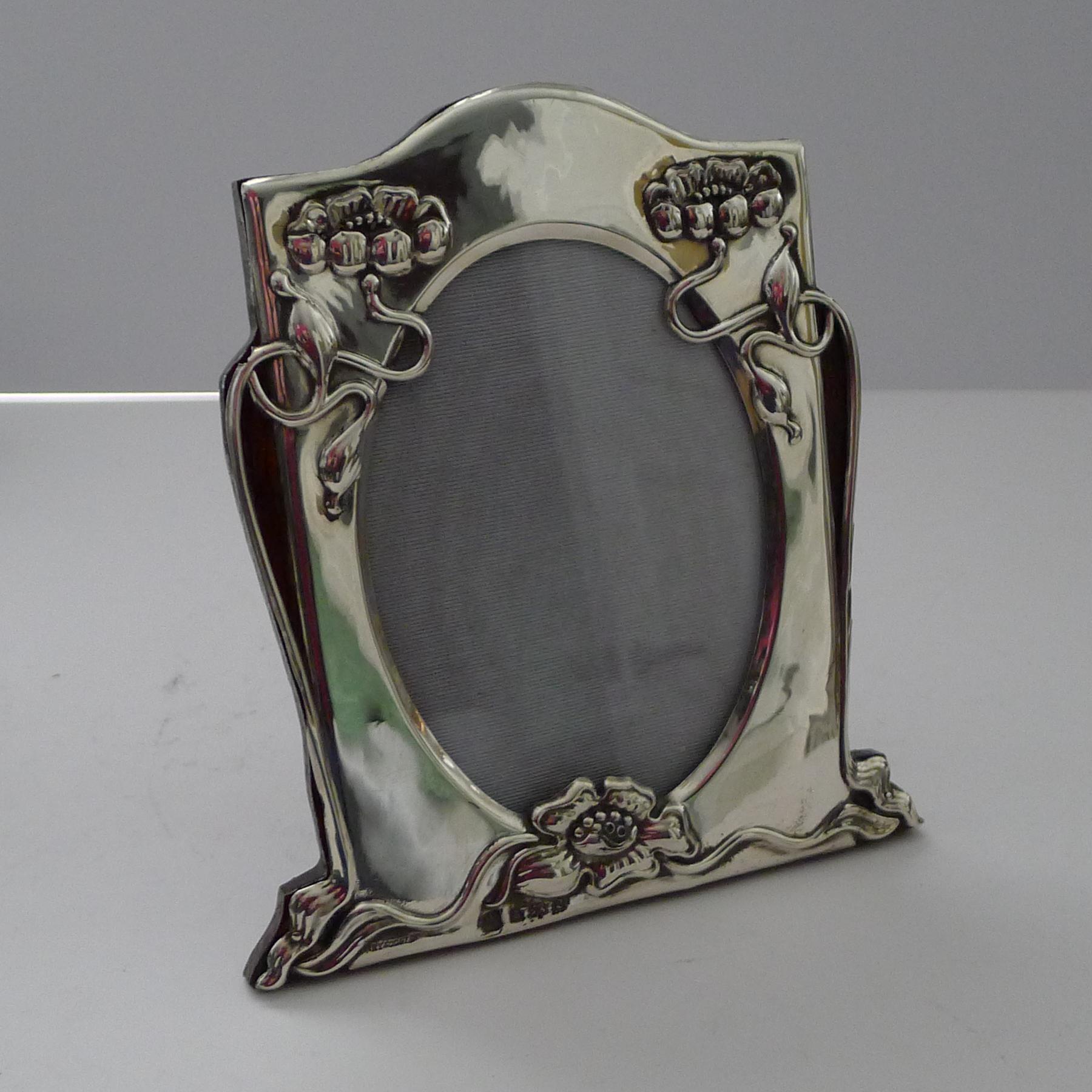 A truly stylish antique English sterling silver photograph frame backed in solid English Oak, incorporating a folding easel stand.

Beautifully decorated with stylised flowers, the silver is fully hallmarked for Birmingham 1902 together with the