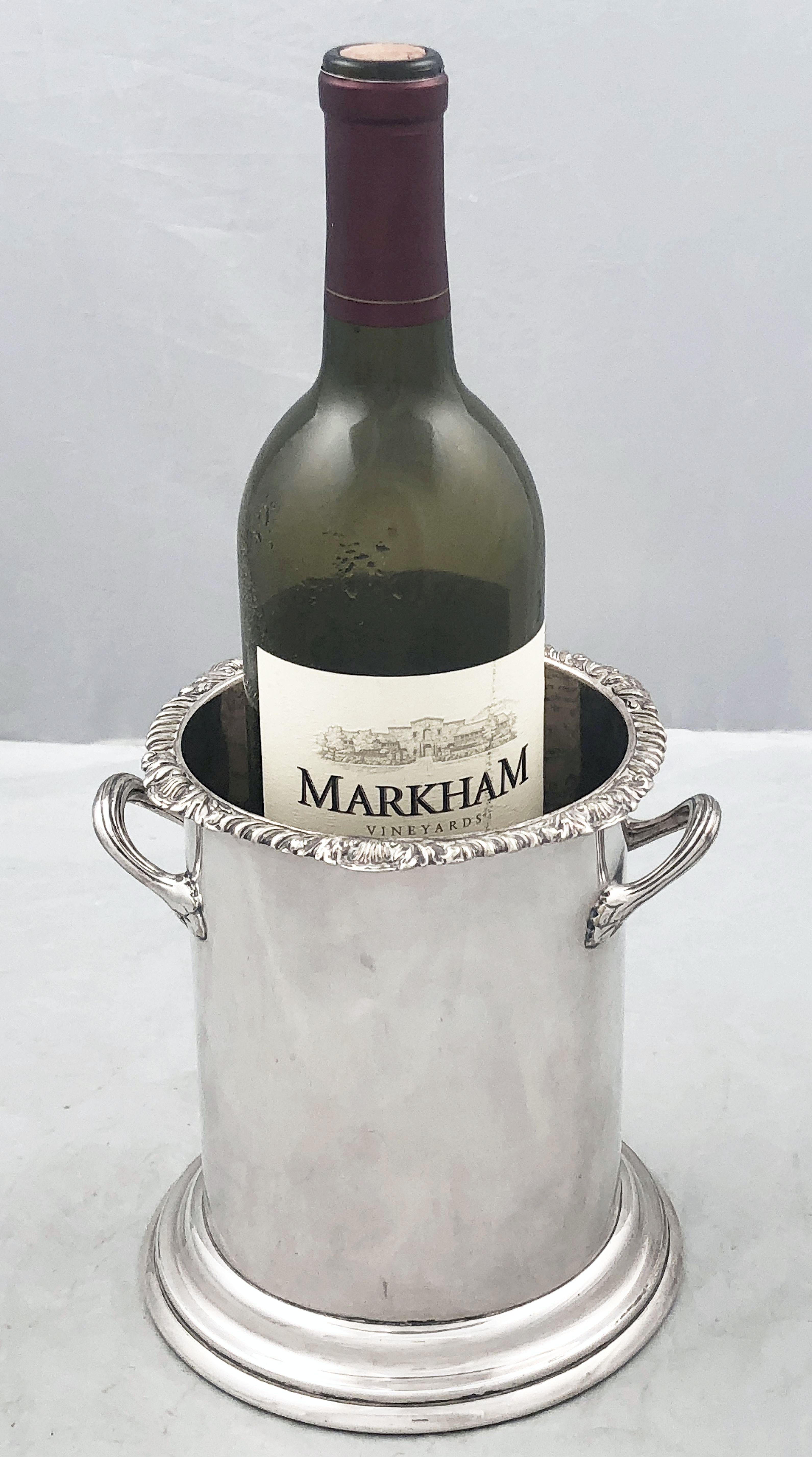 A handsome English wine and champagne bottle display holder or coaster of fine plate silver, featuring a chased top edge, stylish opposing handles, and raised cylindrical base.

Designed to add a fine level of elegance to the presentation of wine at