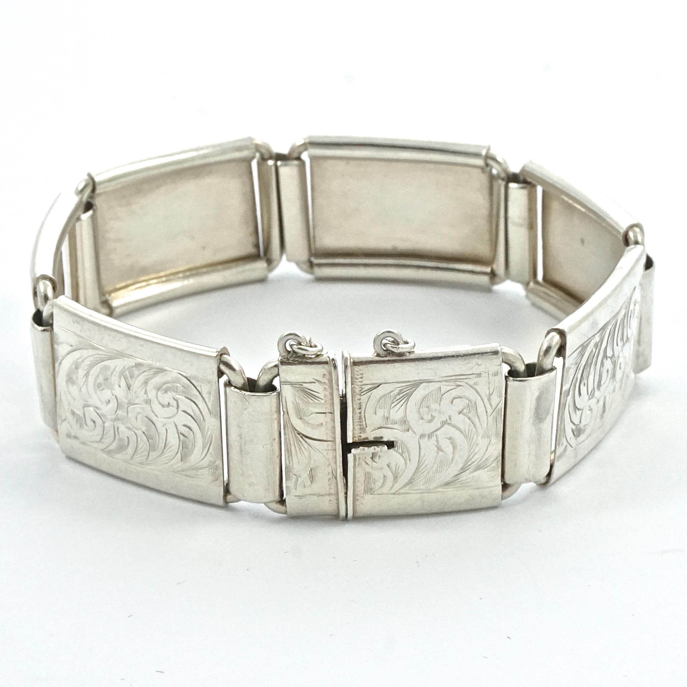 English silver hand engraved scroll panel link bracelet with a safety chain. Measuring length 16.6cm / 6.5 inches by width 1.65cm / .65 inch. The bracelet is stamped 'Silver' and 'Made in England', and tests for silver. The bracelet is in good