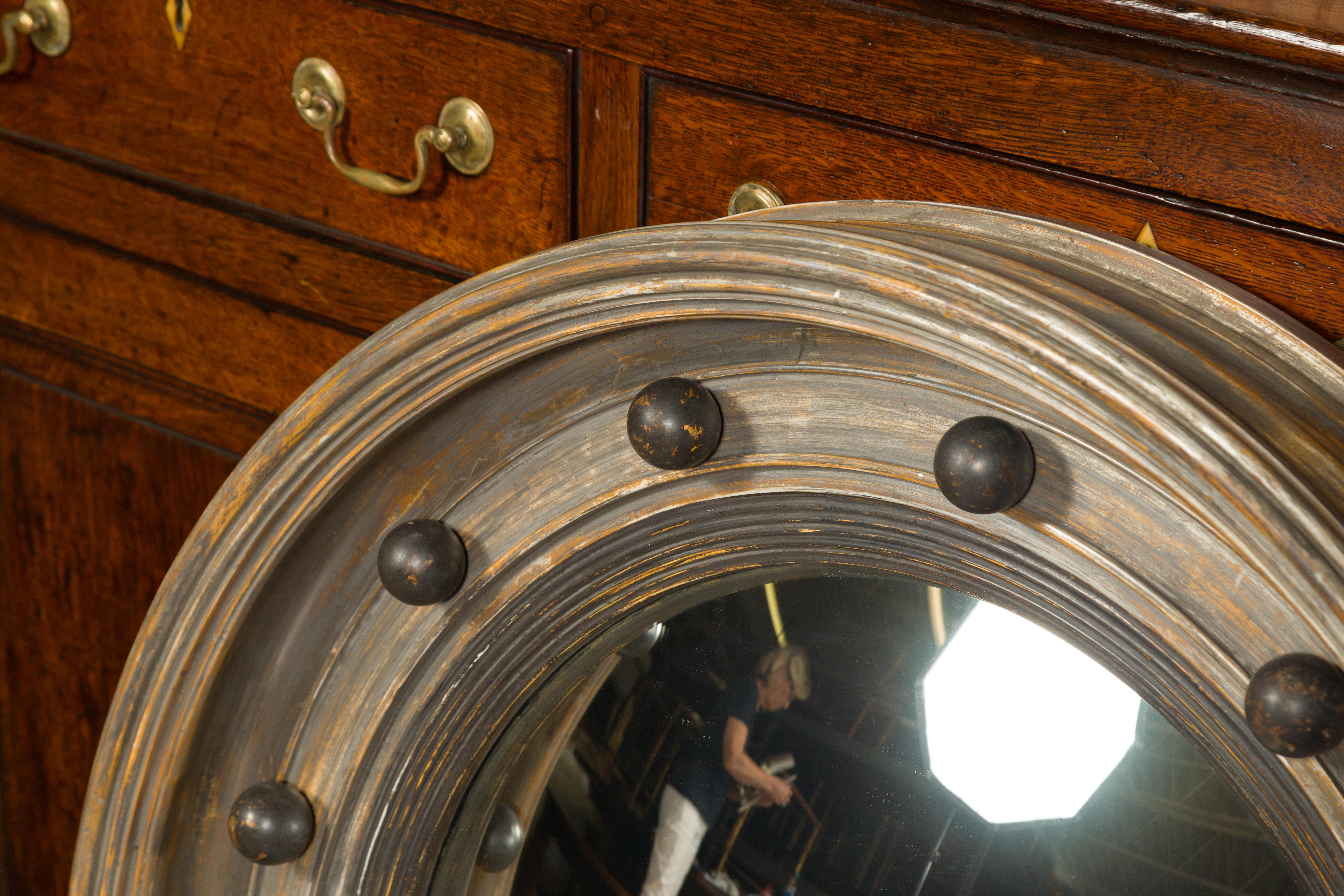 An English silver leaf midcentury bullseye mirror with petite spheres and convex mirror. Created in England, this midcentury mirror features a circular molded wooden frame adorned with new silver leaf and delicately accented with petite spheres,