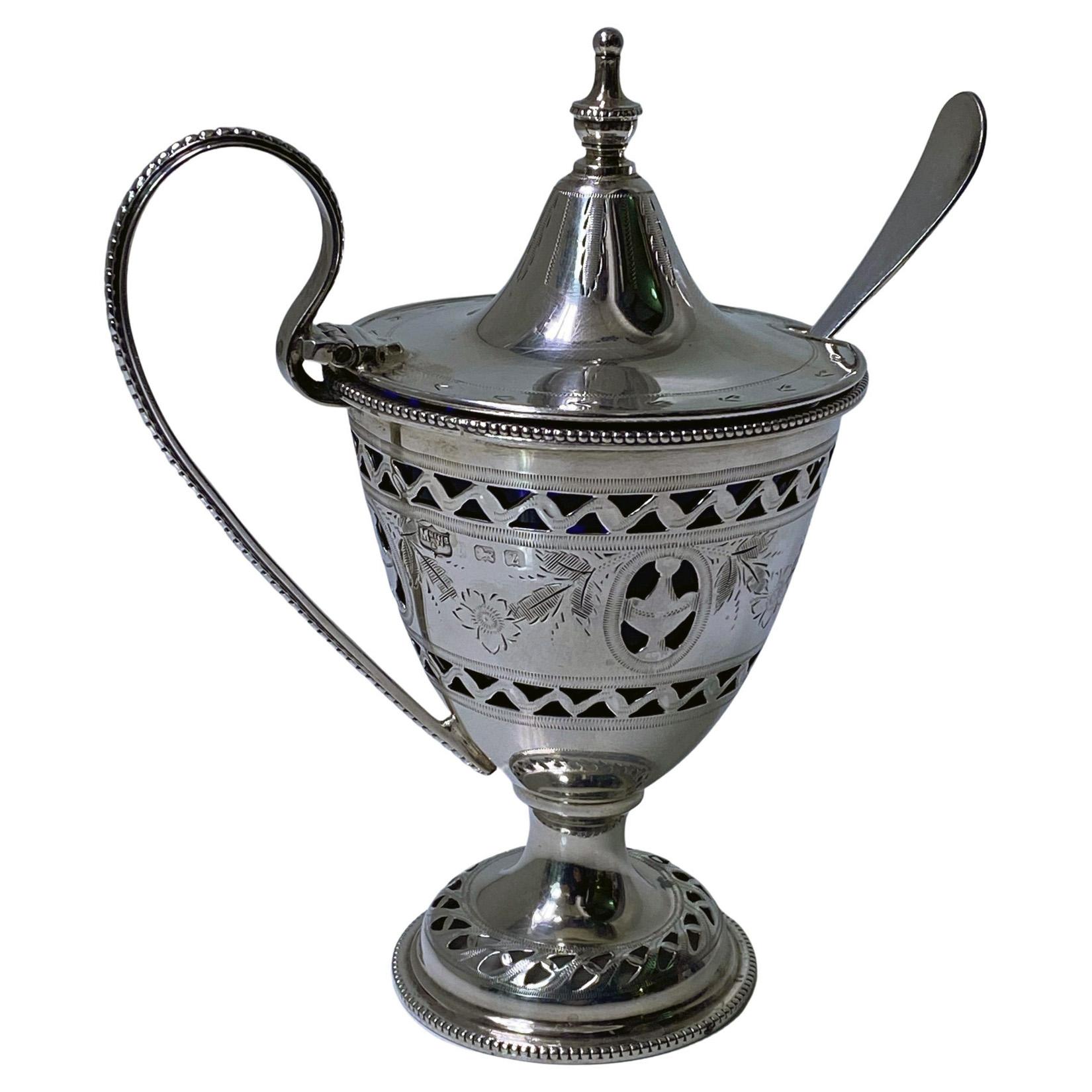 English silver mustard pot London 1924 Mappin and Webb. The mustard of 18th century Georgian neoclassical form, vase shape with pierced work and garland foliate design, bead borders and handle, domed cover with urn shape finial. Fully hallmarked to