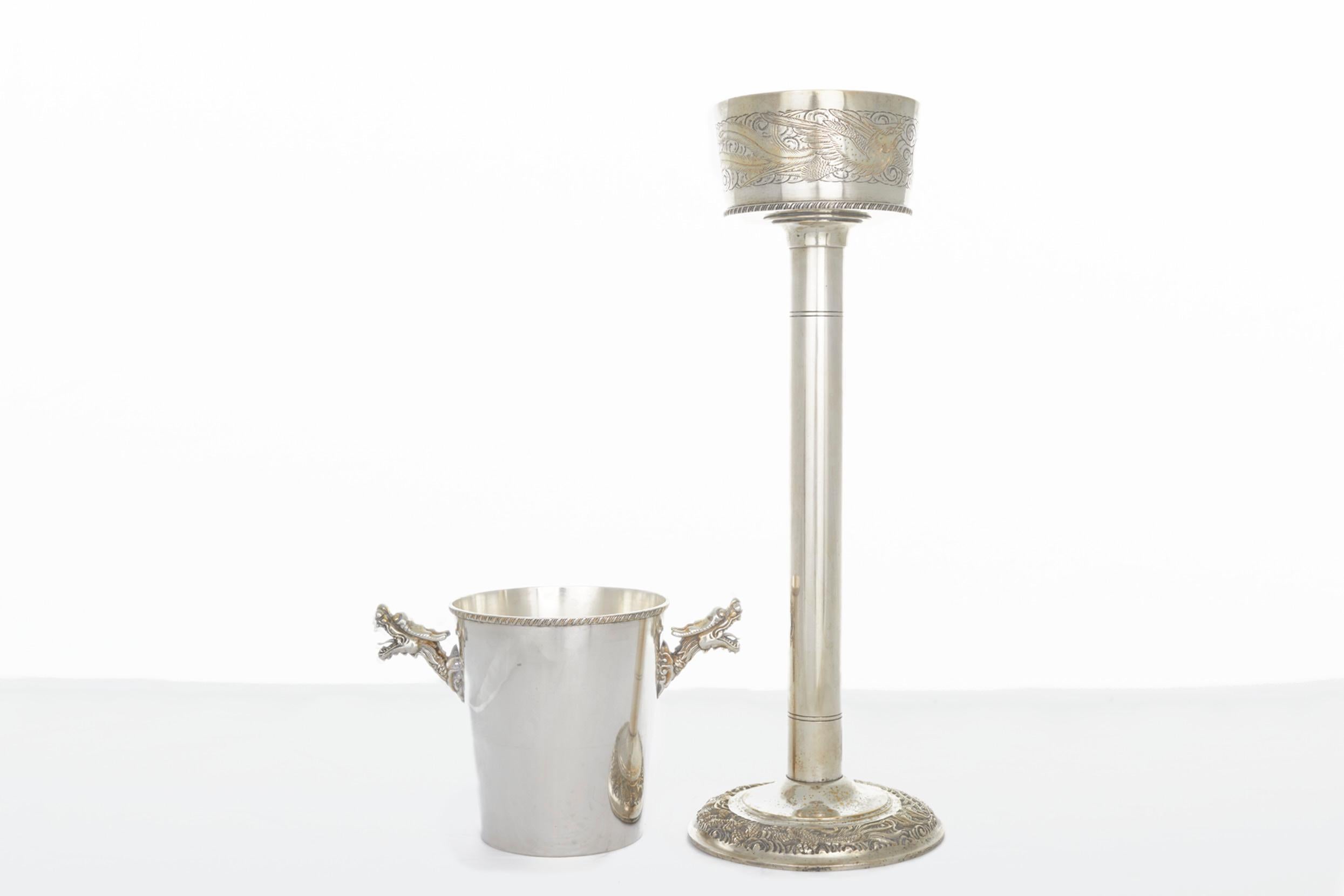 Early 20th century English barware / tableware silver plated champagne bucket / wine cooler on stand. The plated wine cooler / ice bucket features exterior dragon design details on the holding stand and two dragon heads side handles on the bucket.