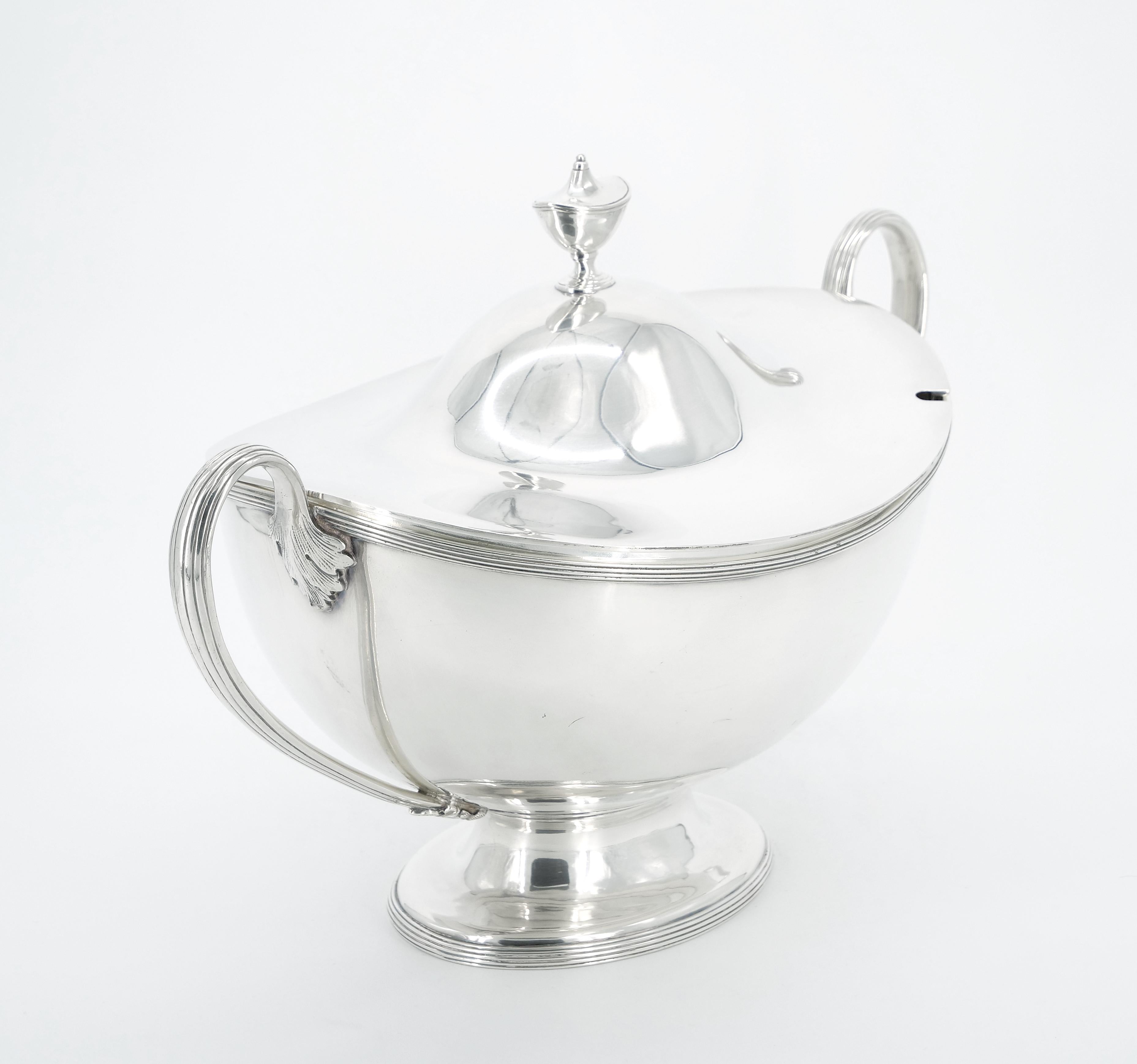 Immerse yourself in the refined elegance of our Large Early 20th Century English Silver Plate Tableware Covered Tureen. This striking piece boasts a sleek and clean Art Deco design, featuring a distinctive boat shape with two gracefully arched,