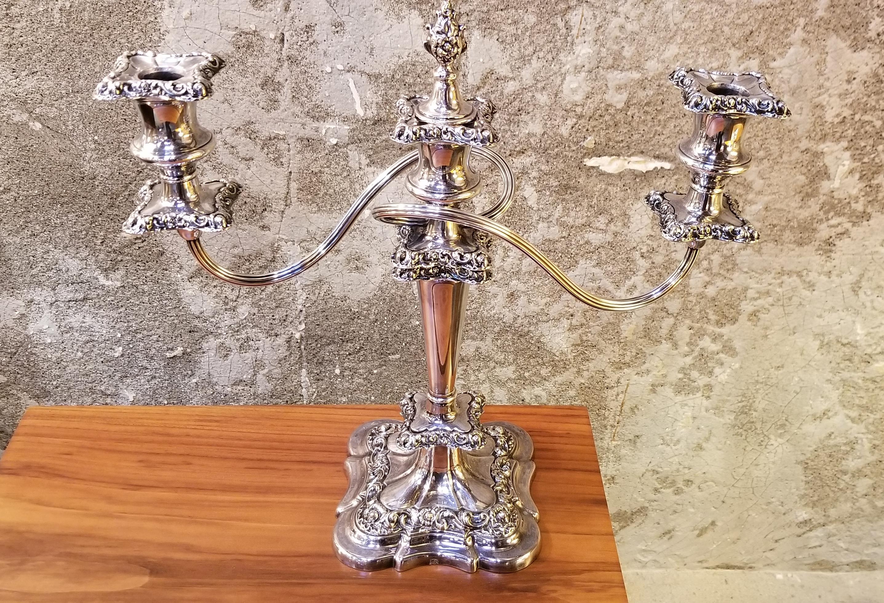 Ornate pair of early 20th century silver plate candlesticks by Barker-Ellis, Birmingham, England, circa. 1912. Detailed floral repousse, retaining original center finial, iron weighted bases, beautiful patina to silver.