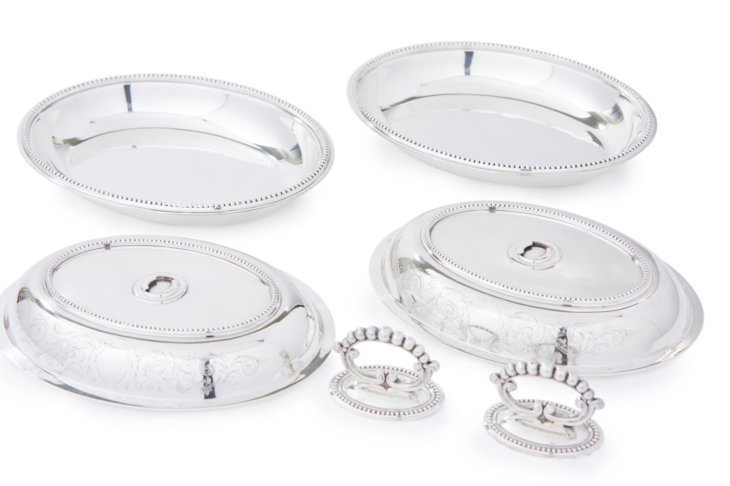 English silver plate pair of oval shape covered entrée dishes with detachable top handles with exterior cast bead borders and floral design detail. The reversible tops can be used as separate open dishes. Great condition with minor wear. Maker's